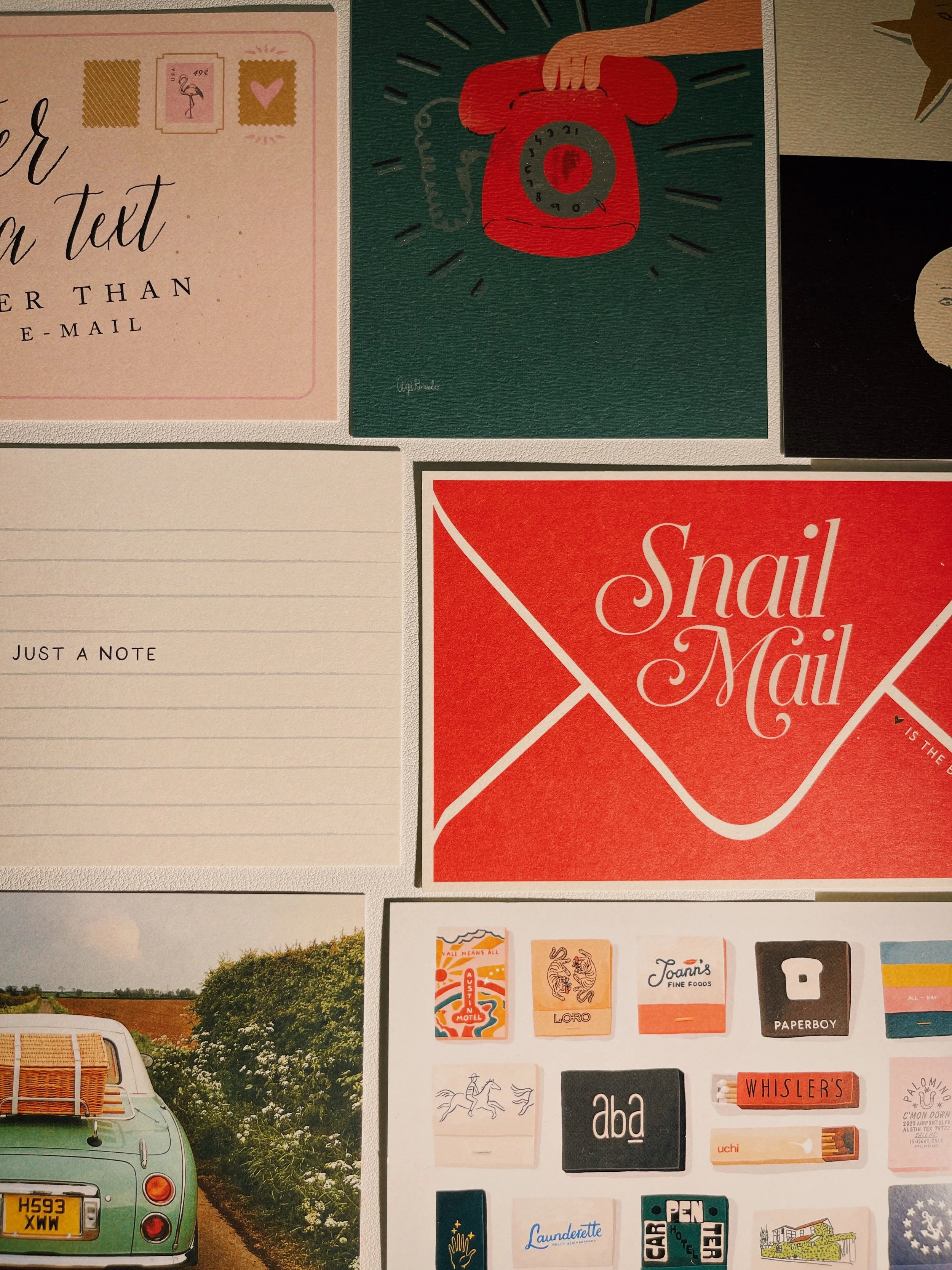 Postcards laid out on a desk for Edition 01 of The Postcard Société, postcard correspondence subscription box curated by social and cultural psychologist and travel psychologist Dr. Katie Blake, PhD.