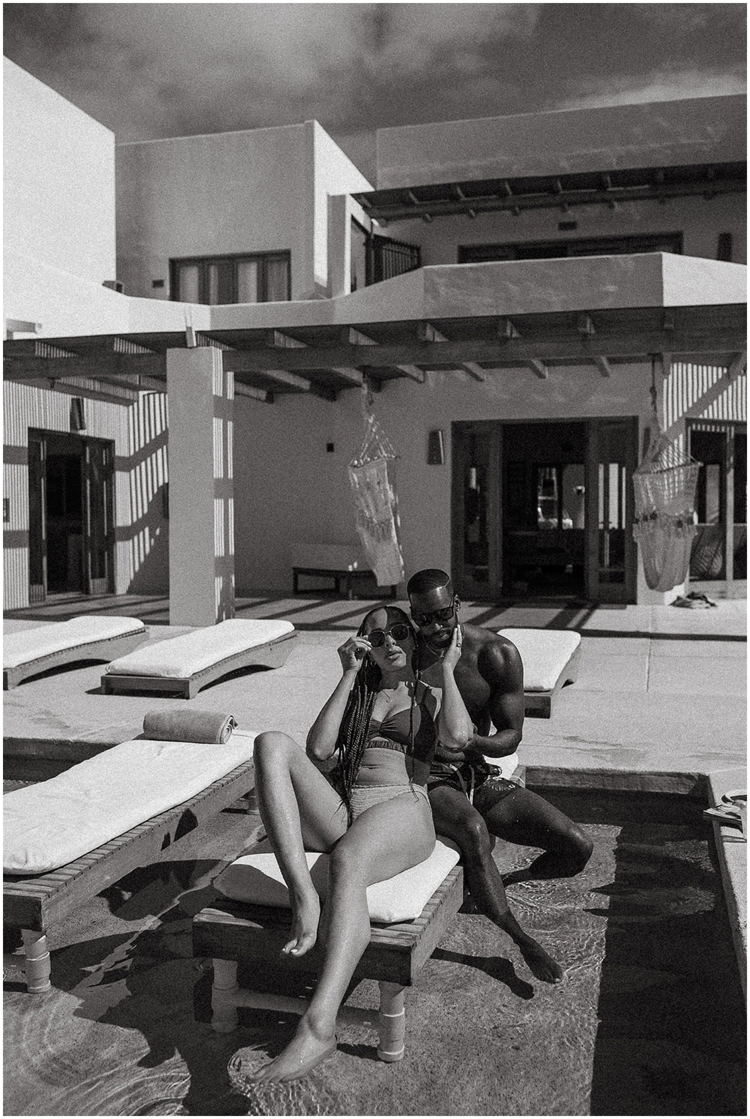 black and white photo of couple lounging by pool