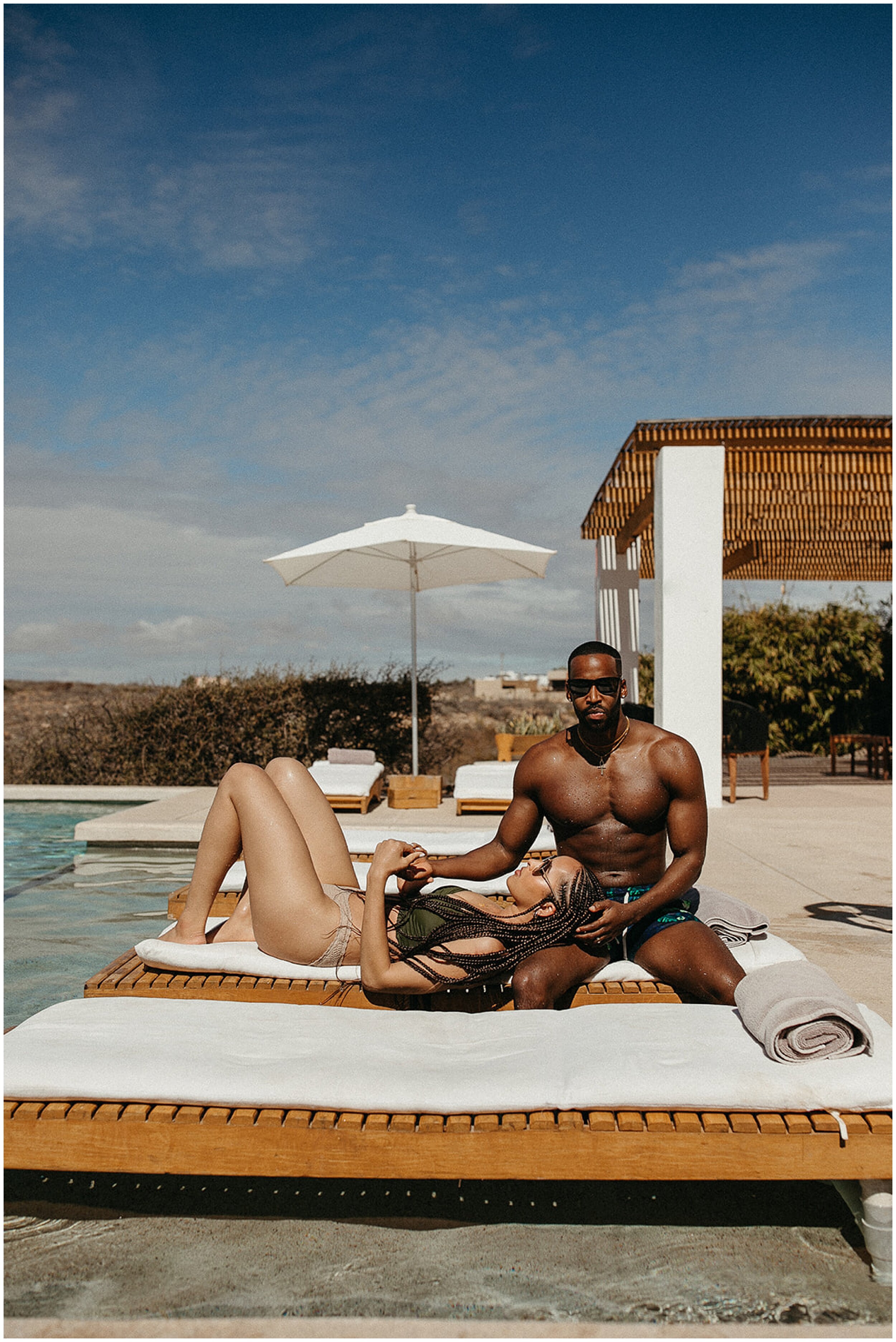 woman laying on man's lap by pool