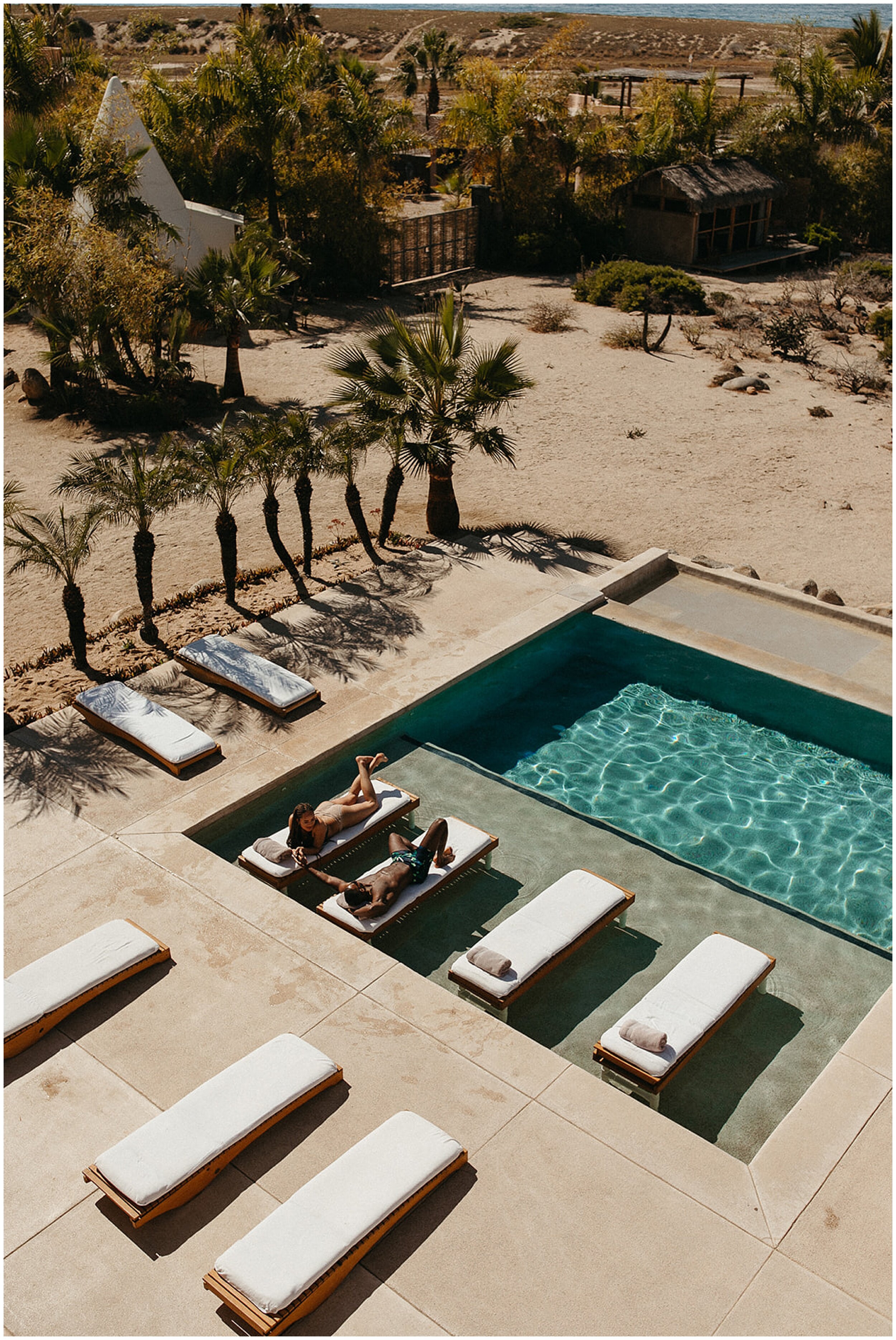 couple laying on chairs by pool