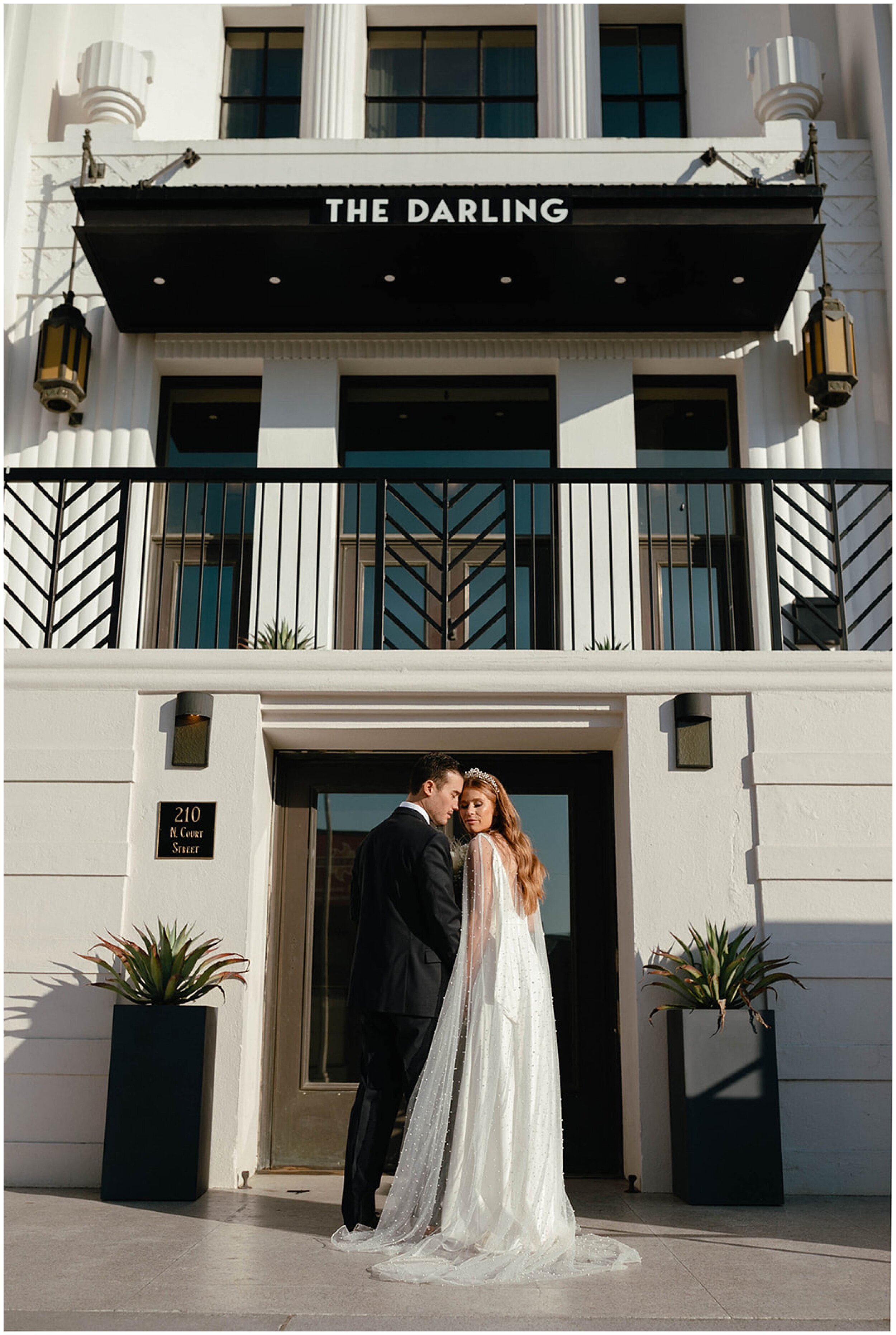 bride and groom standing in front of building