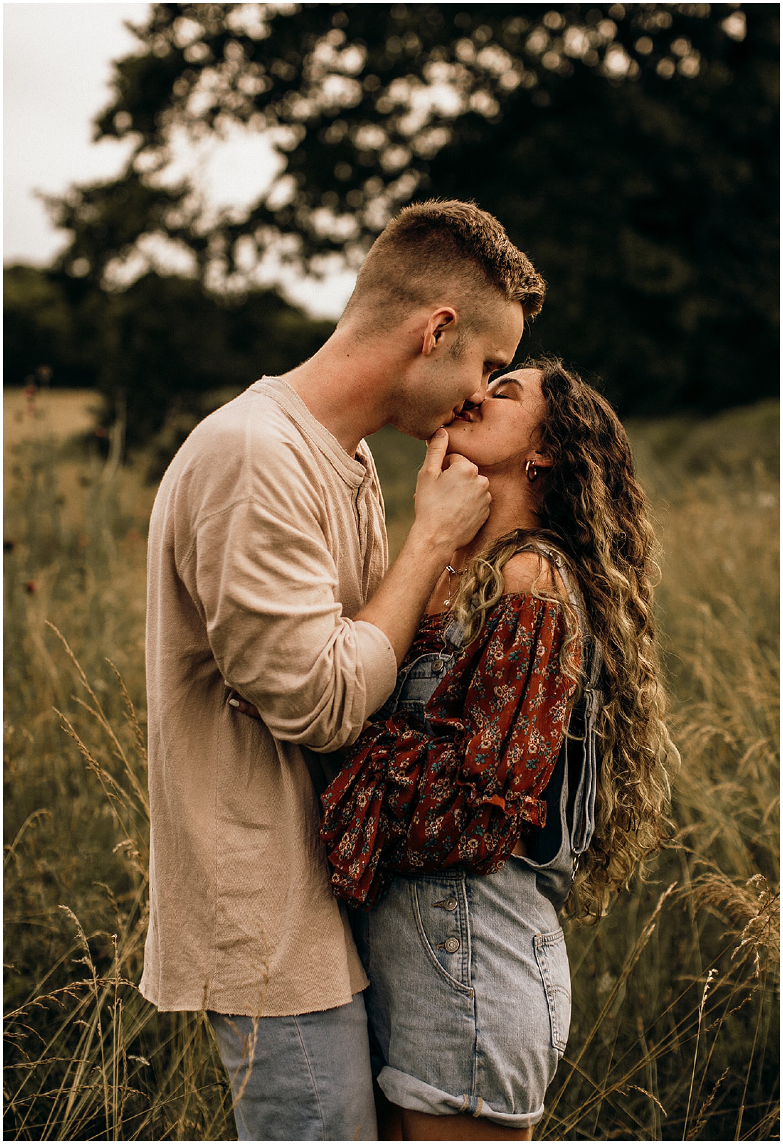 couple kissing in field under trees
