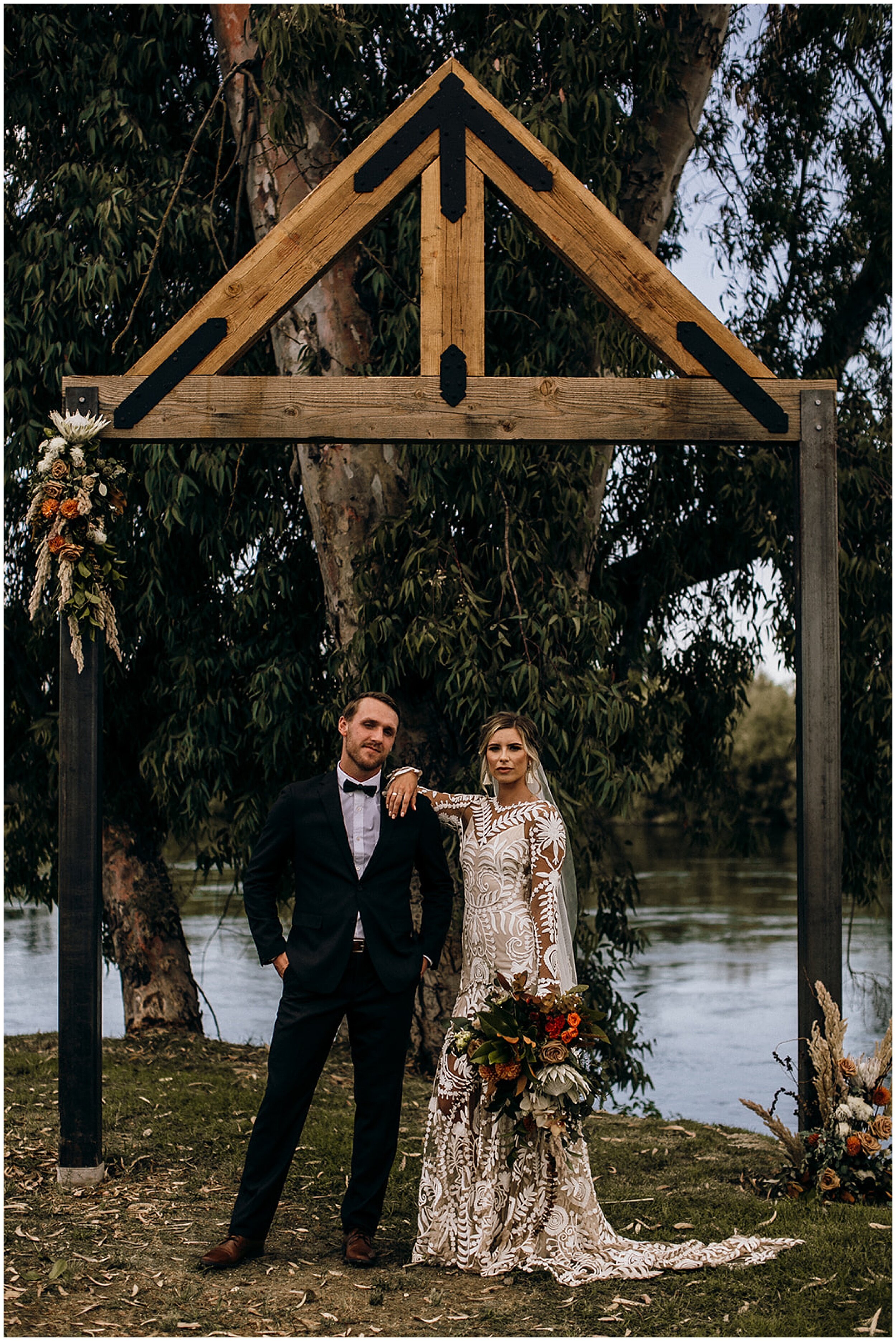 bride and groom posing under arbor