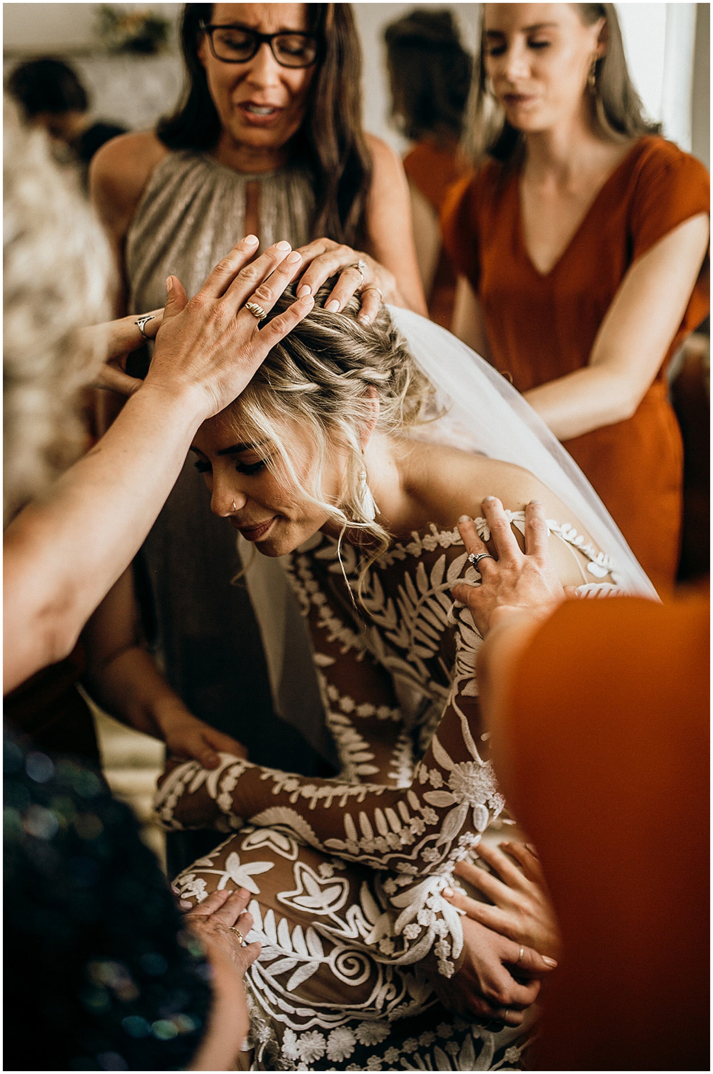 bridesmaids praying over bride