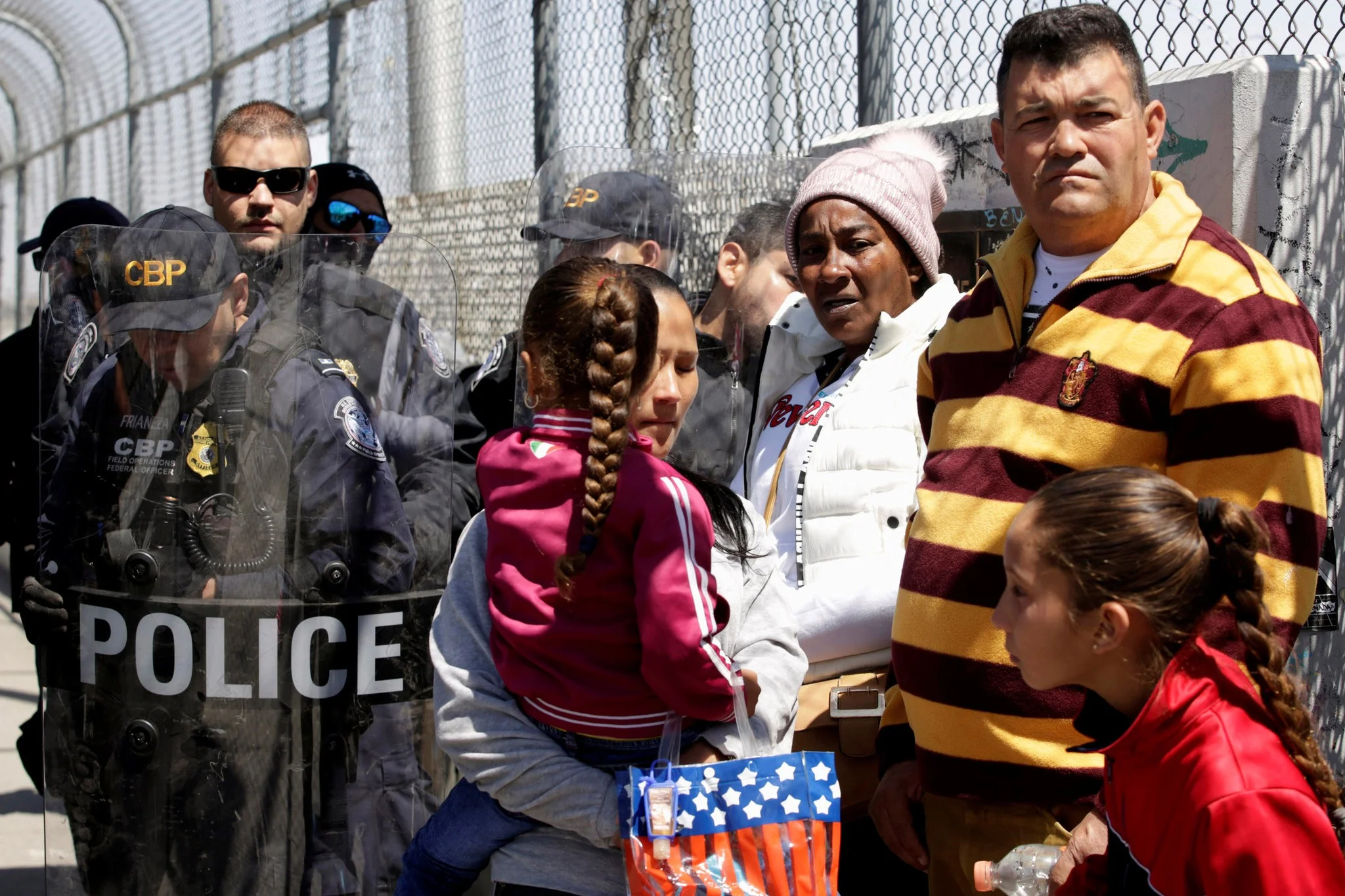 Customs and Border Protection agents with migrants hoping to apply for asylum at the border between Mexico and the United States. Credit Jose Luis Gonzalez/Reuters