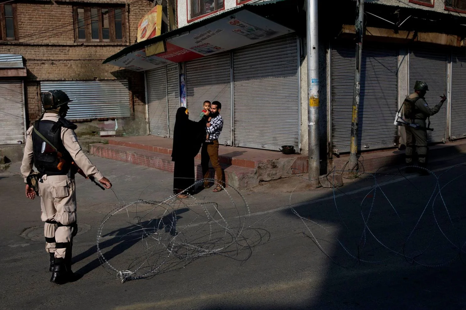 In this Friday, Aug. 23, 2019, file photo, a Kashmiri family waits for a lift to take their sick child to hospital as Indian paramilitary soldiers stand guard near a checkpoint during lockdown in Srinagar, Indian controlled Kashmir. India’s top court is taking up legal challenges to the government’s decision to revoke Indian-controlled Kashmir’s special status and has asked the government to explain its stance to the court. The Supreme Court held a preliminary hearing on the petitions Wednesday, Aug. 28, and said five judges will start a regular hearing in October. (Dar Yasin, File/Associated Press)
