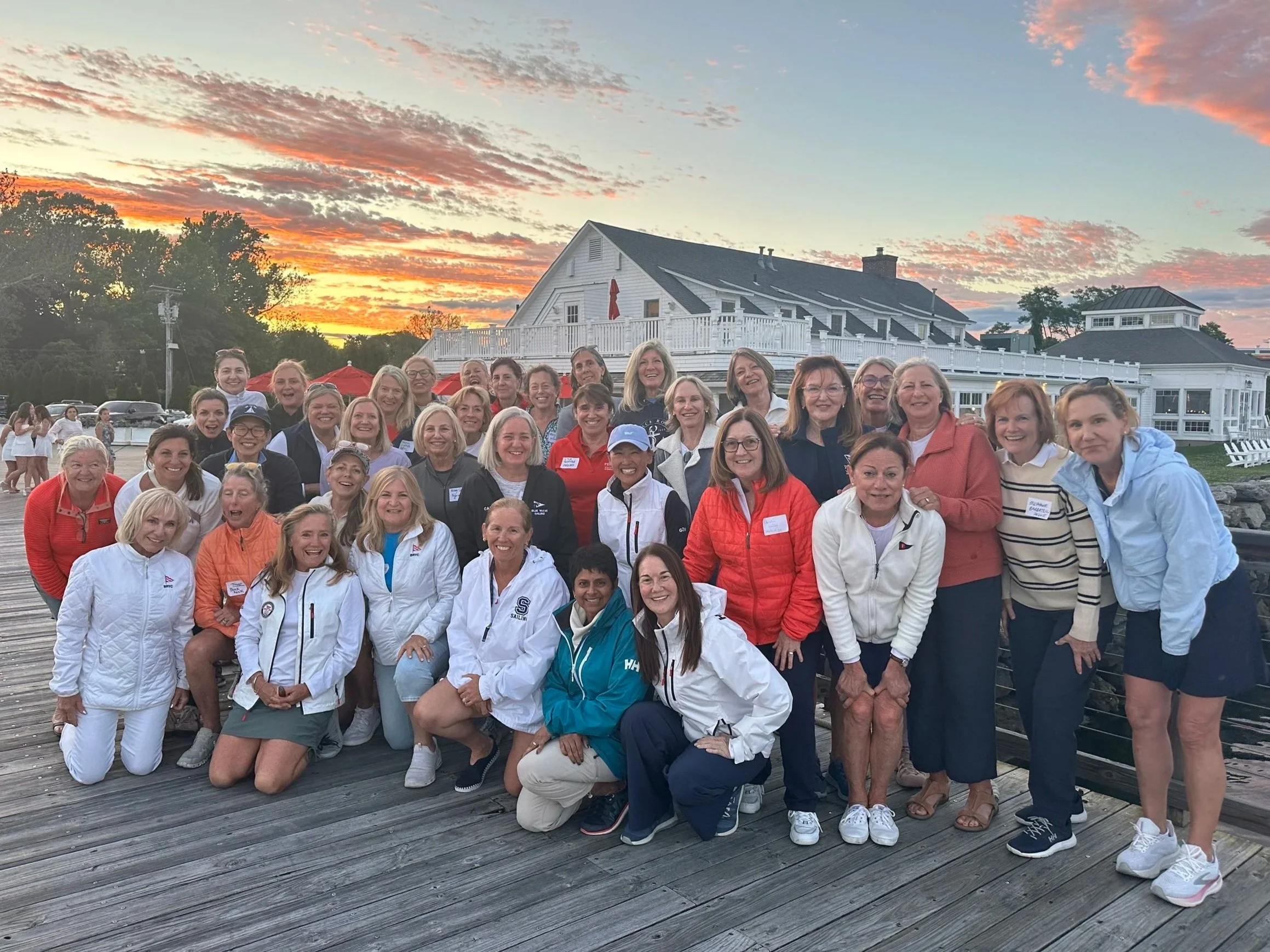 Women on the Water Black Rock Yacht Club women sailors gather on the dock after the 2026 WOW Supper Series, with an incredible sunset in the background!