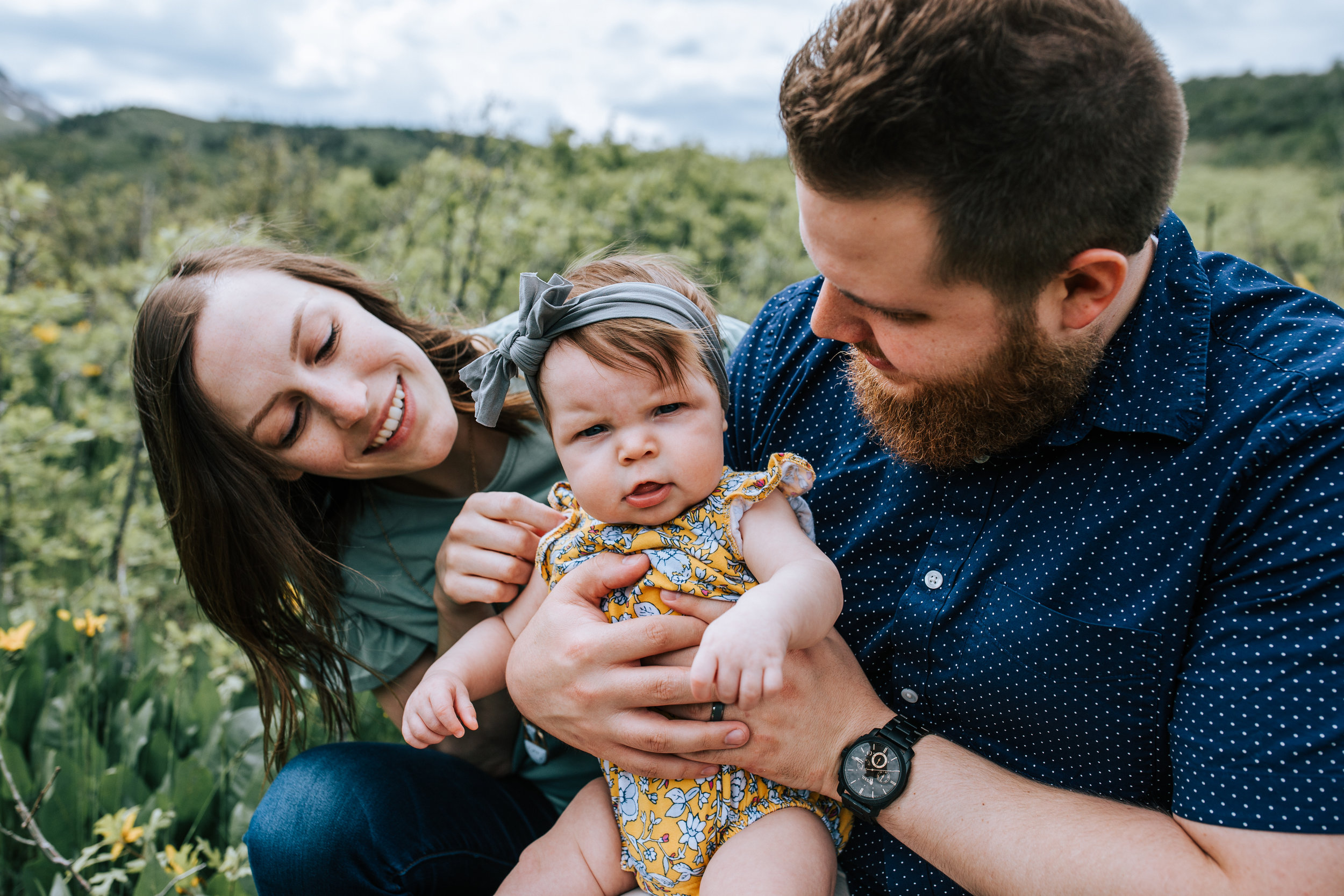 Windy family photos parents and baby in wildflower field