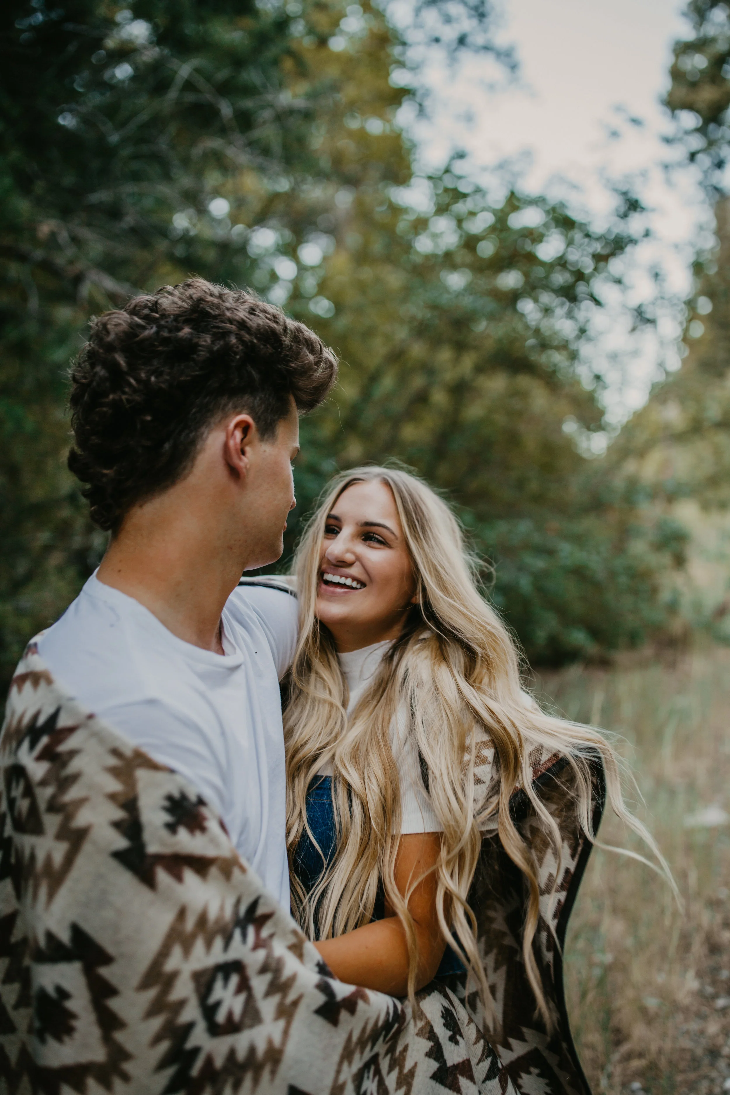 Romantic forest engagement session couple wrapped in blanket in Utah mountains long blonde hair