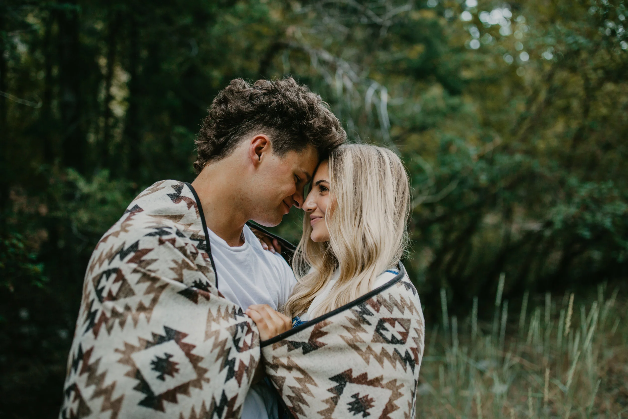 Romantic forest engagement session couple wrapped in blanket in Utah mountains long blonde hair
