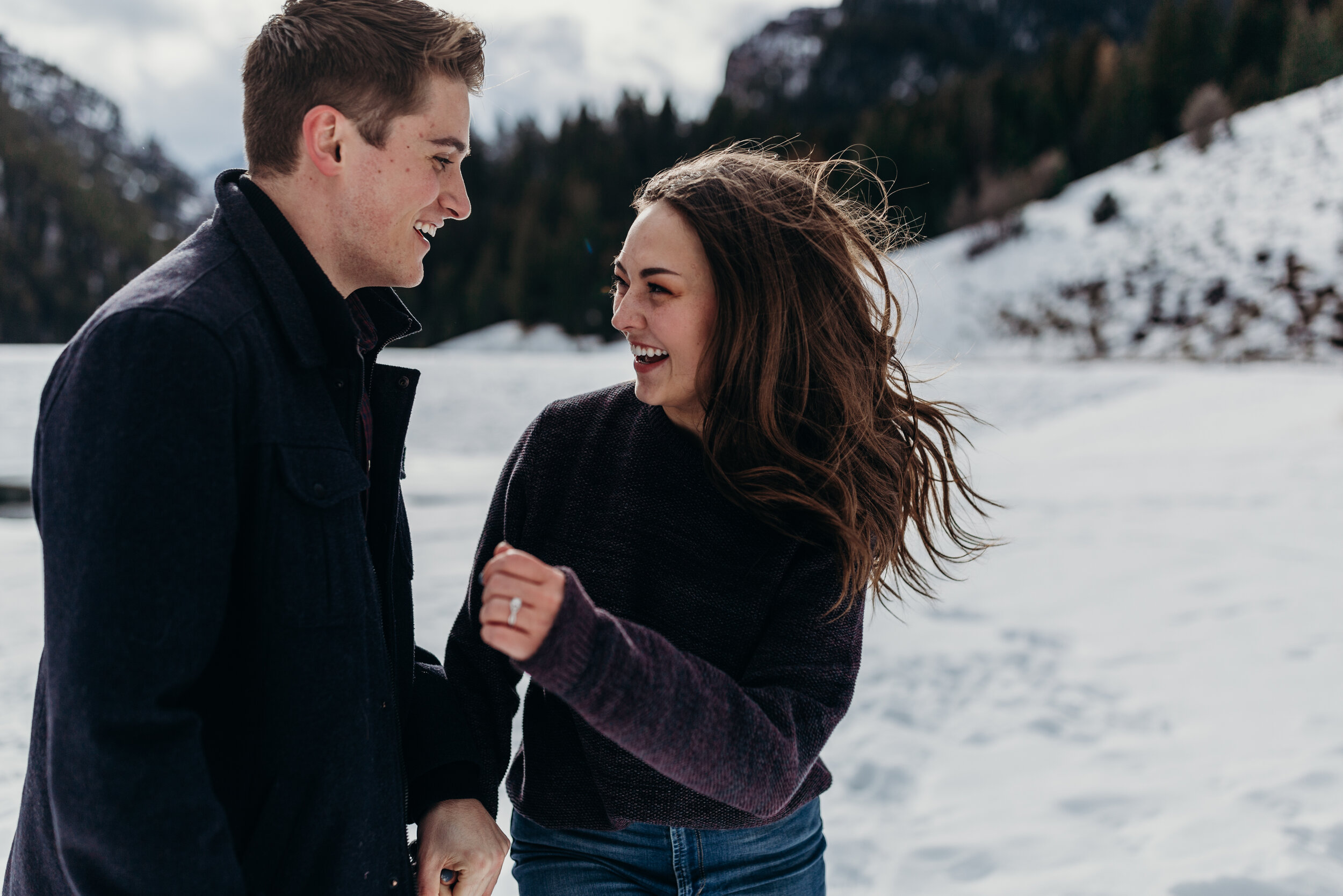 Playful snowy winter mountain engagements windy hair pine trees laughing couple shoot #coupleshoot #utahphotographer #weddingphotographer #engagements #engagementshoot #winterengagements