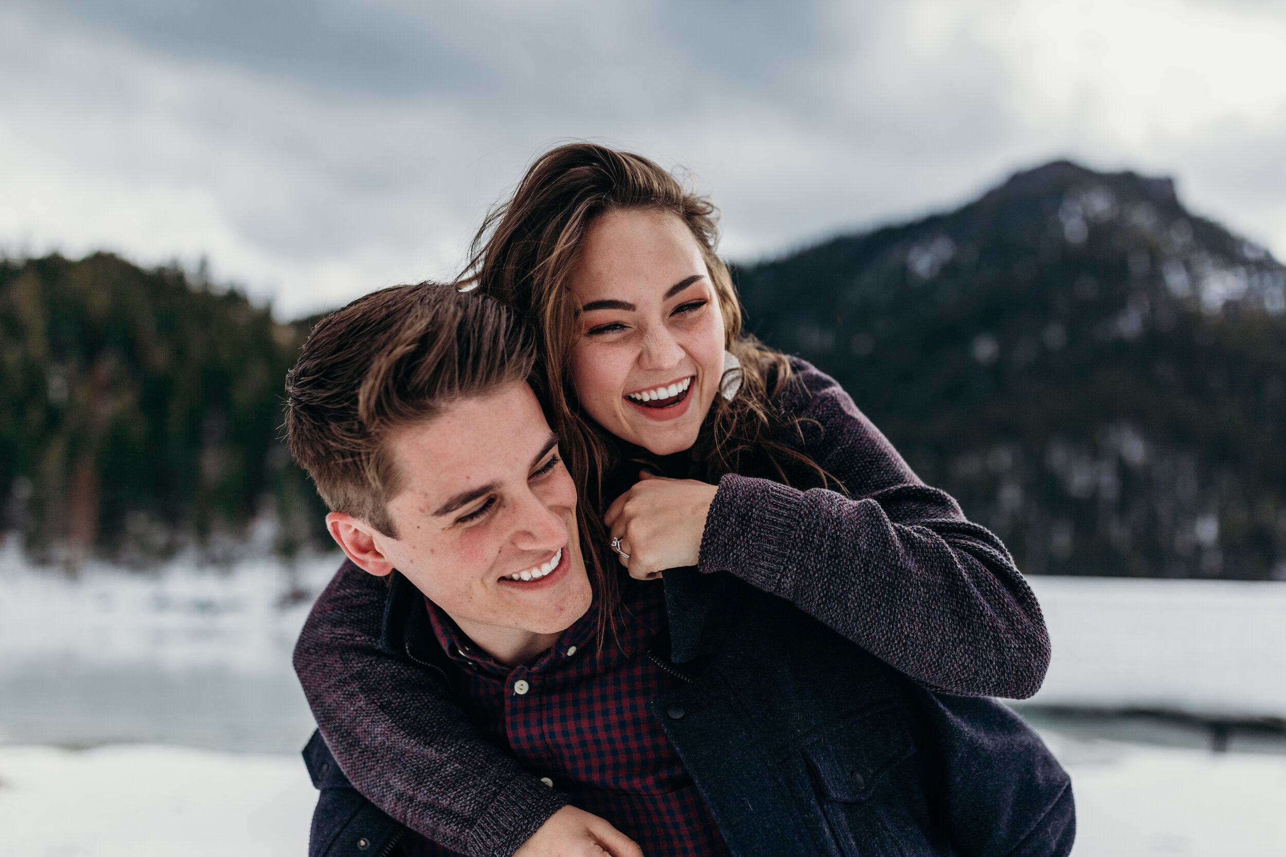 Snowy winter mountain engagements windy hair pine trees laughing couple shoot #coupleshoot #utahphotographer #weddingphotographer #engagements #engagementshoot #winterengagements piggy back