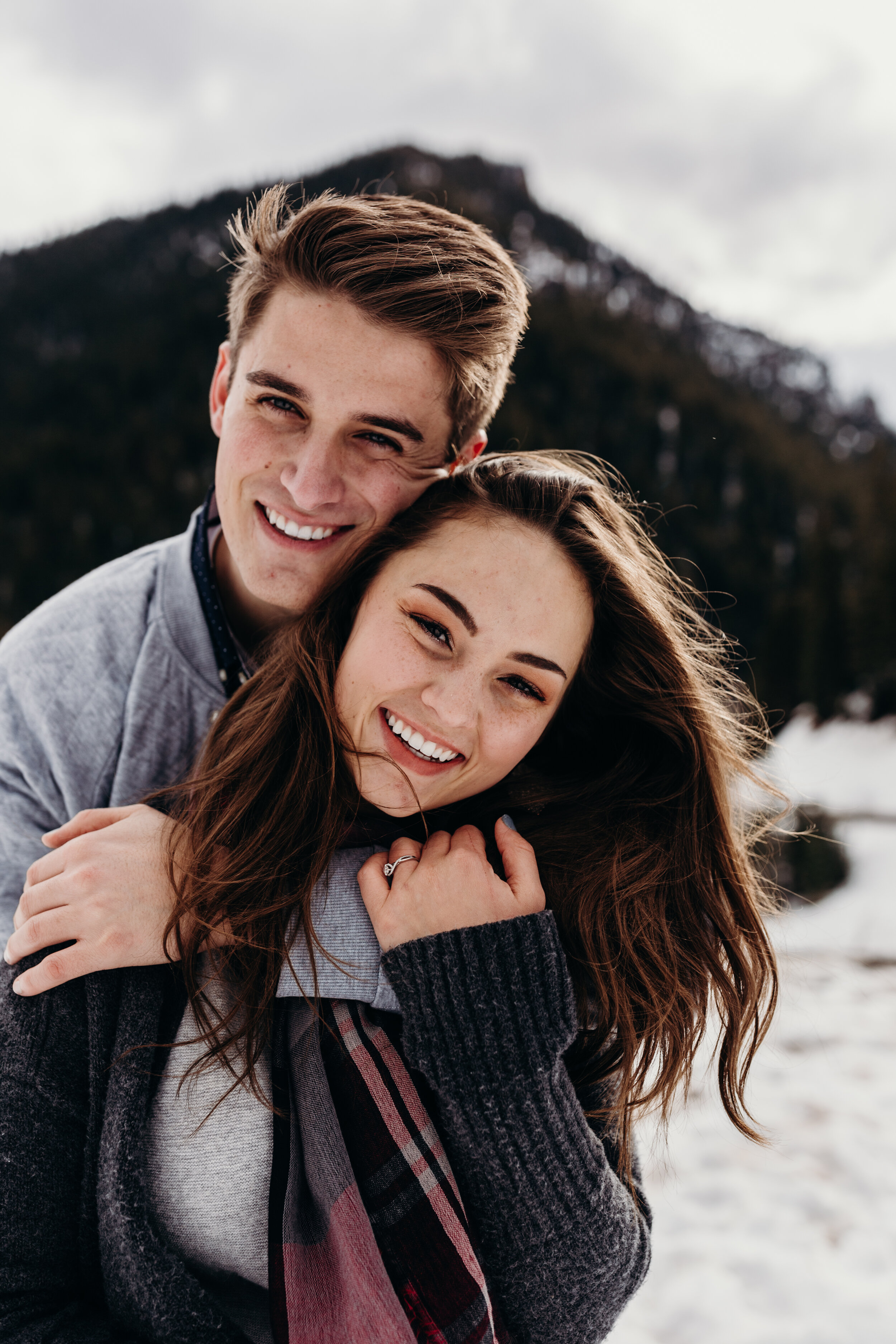 Snowy winter mountain engagements windy hair pine trees laughing couple shoot #coupleshoot #utahphotographer #weddingphotographer #engagements #engagementshoot #winterengagements