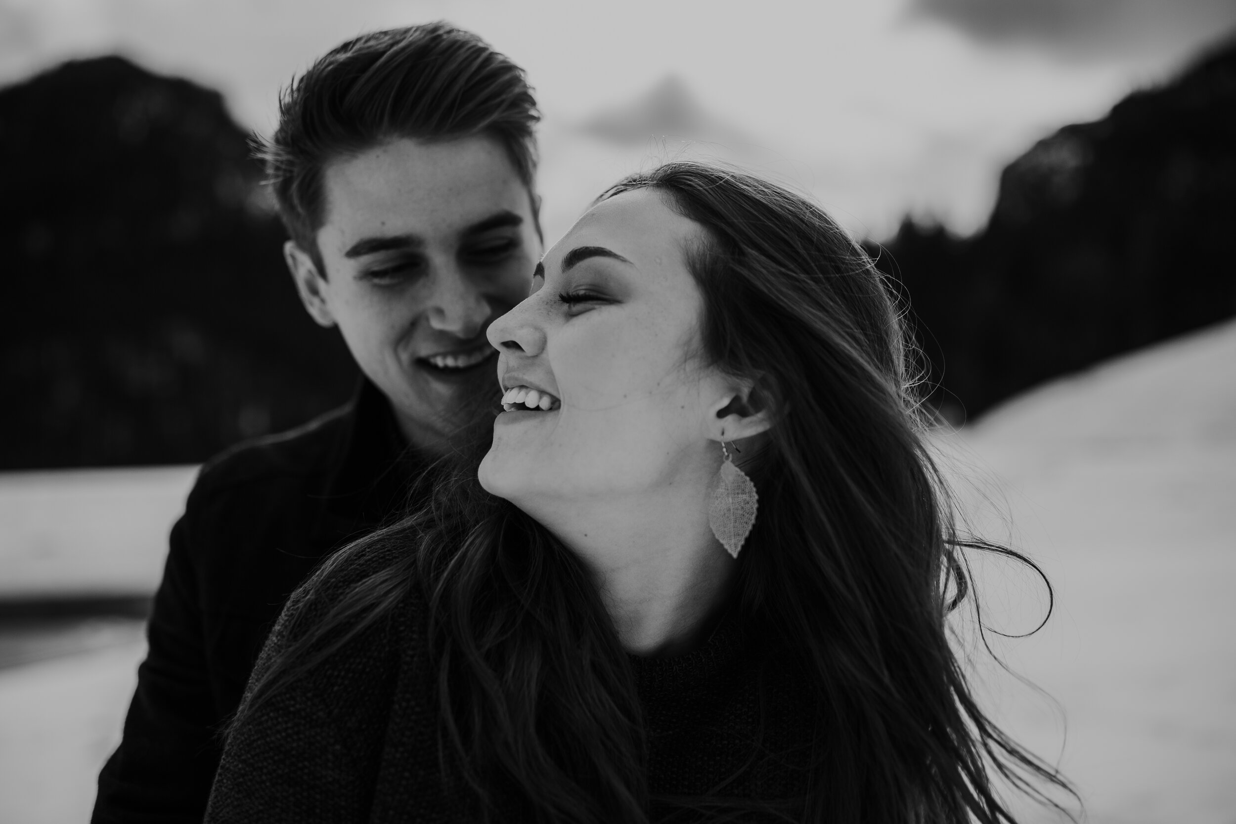 Snowy winter mountain engagements windy hair pine trees laughing couple shoot #coupleshoot #utahphotographer #weddingphotographer #engagements #engagementshoot #winterengagements black and white
