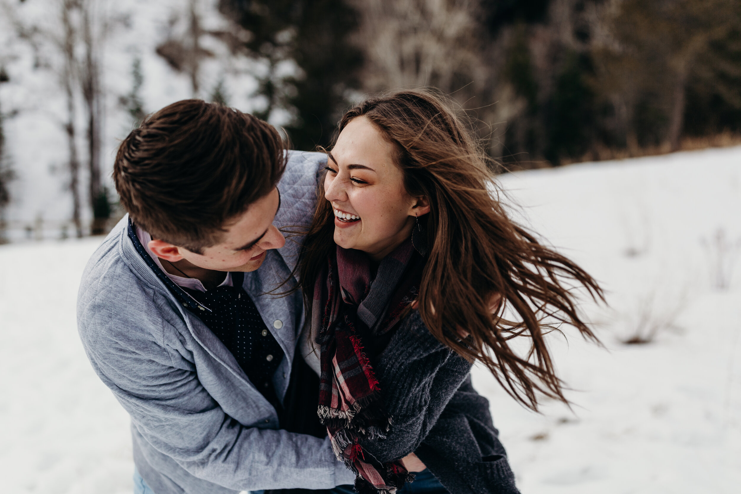 Adventurous snowy winter mountain engagements windy hair pine trees laughing couple shoot #coupleshoot #utahphotographer #weddingphotographer #engagements #engagementshoot #winterengagements