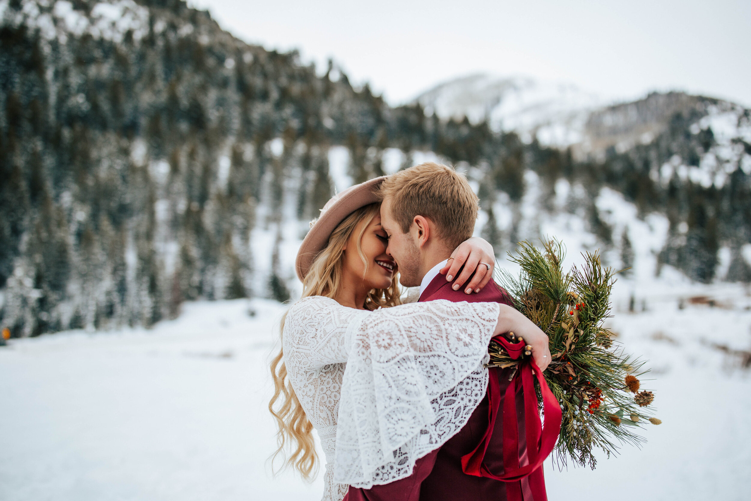 Snowy winter mountain bridal shoot bride and groom maroon suit bouquet pine trees Utah mountain wedding elopement photographer #utahphotographer #weddingphotographer #elopement #elopementphotographer