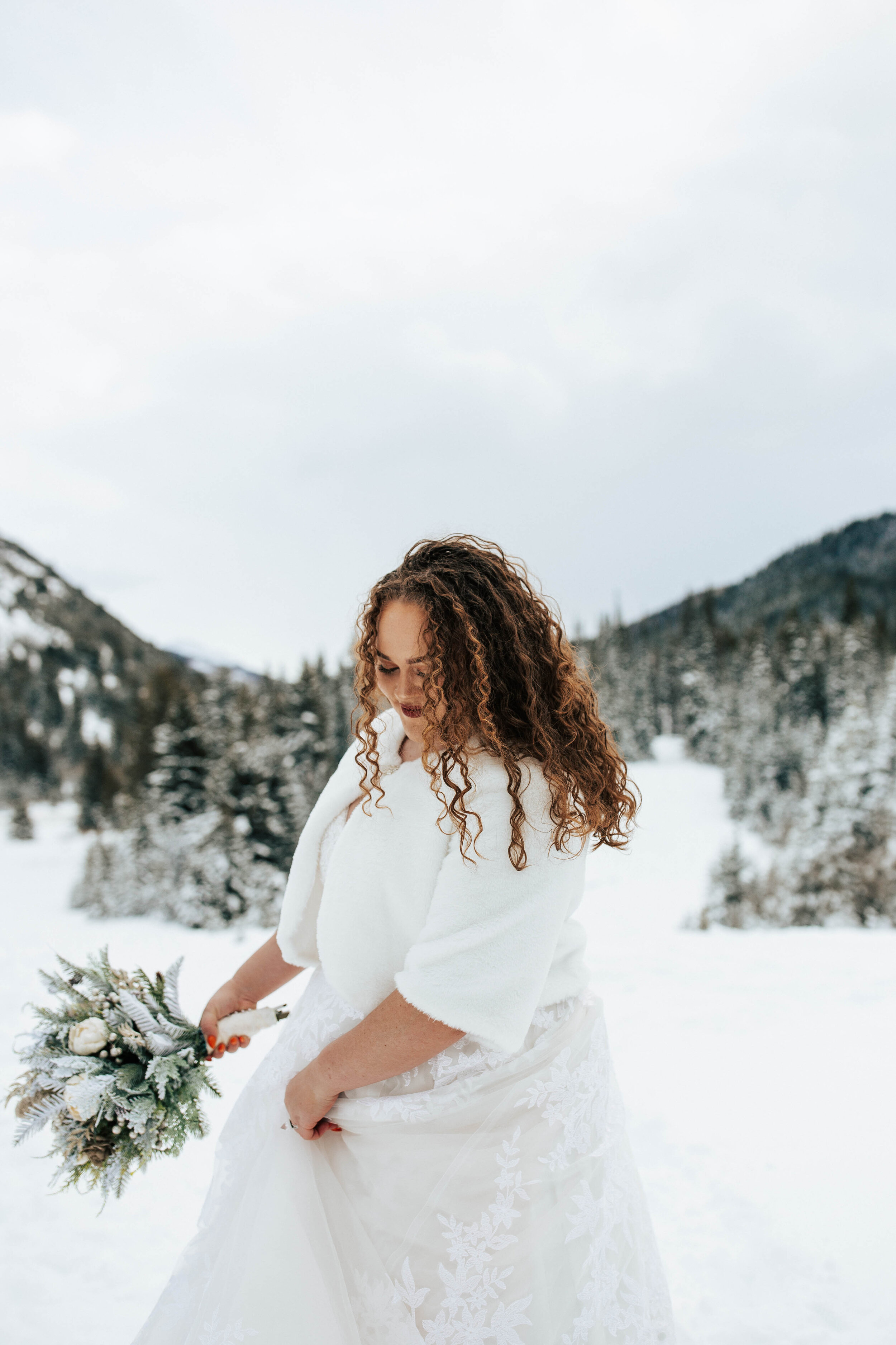 Snowy mountain winter bridals long curly hair big eyes blue florals wedding dress bride #utahphotographer #weddingphotographer #bride #bridals wedding dress flax fur shawl
