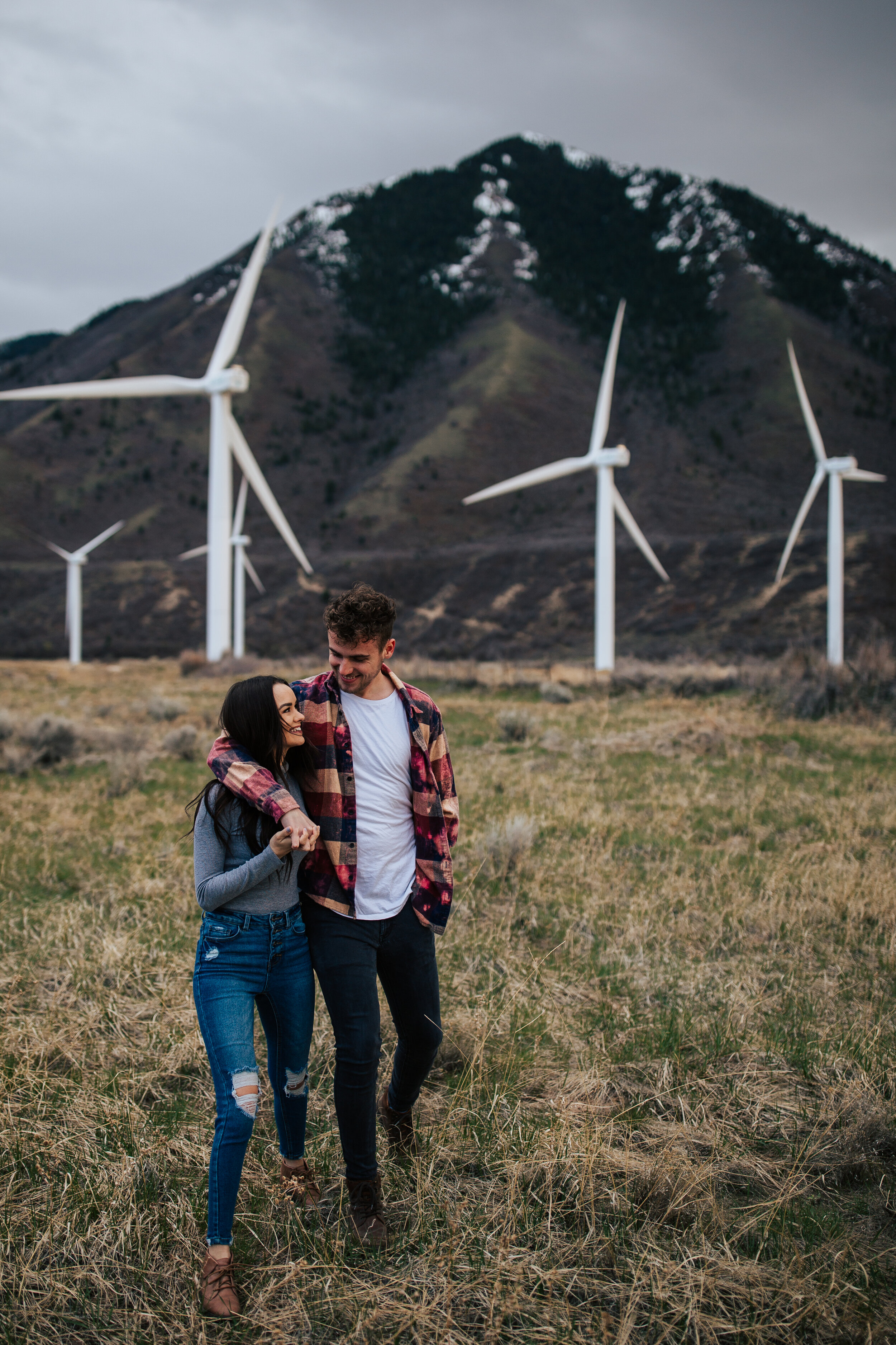 Overcast windy adventurous couples session windmills moody evening shoot. Engagement session. Utah wedding photographer. #utahphotographer #oregonphotographer #washingtonphotographer #coupleshoot