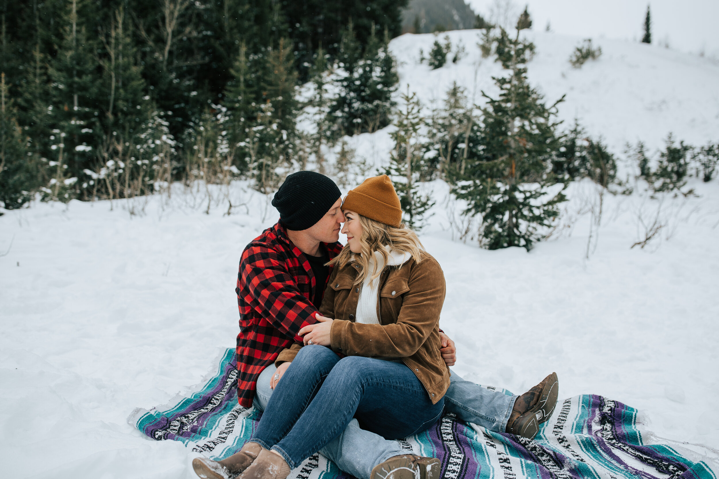 Winter engagement session in Utah mountains Big Cottonwood Canyon engagement shoot #utahphotographer #winterengagements couple wrapped in blanket