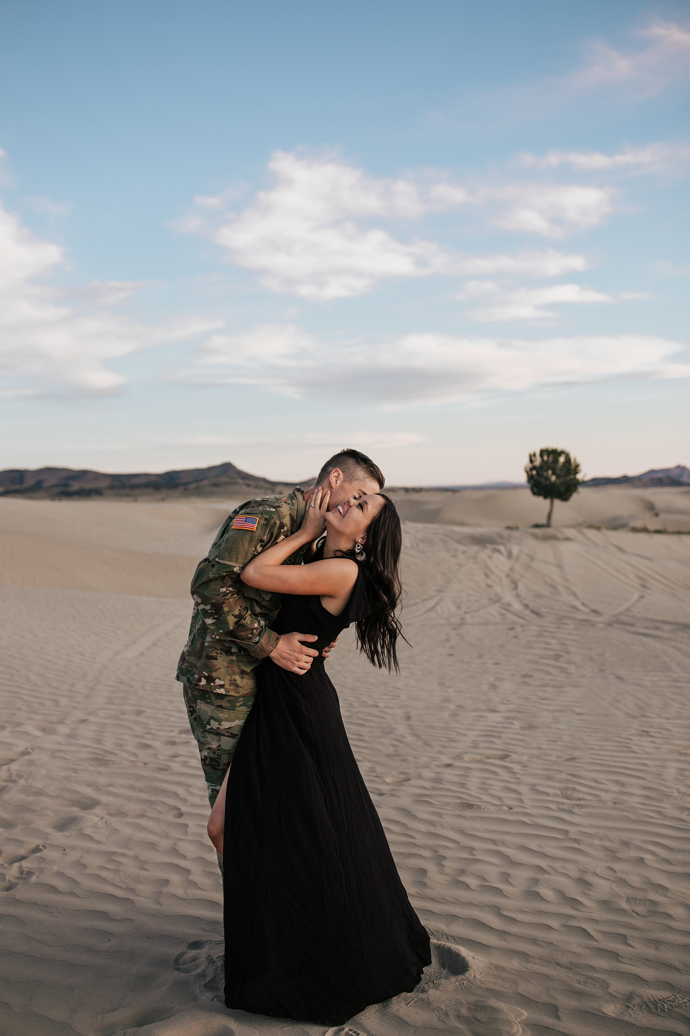  A service man dips and kisses his wife in a dessert in a beautiful and unique honeymoon couples photo shoot. Professional honeymoon photographer Emily Jenkins Photography couple pose inspiration ideas and goals client attire inspiration for military