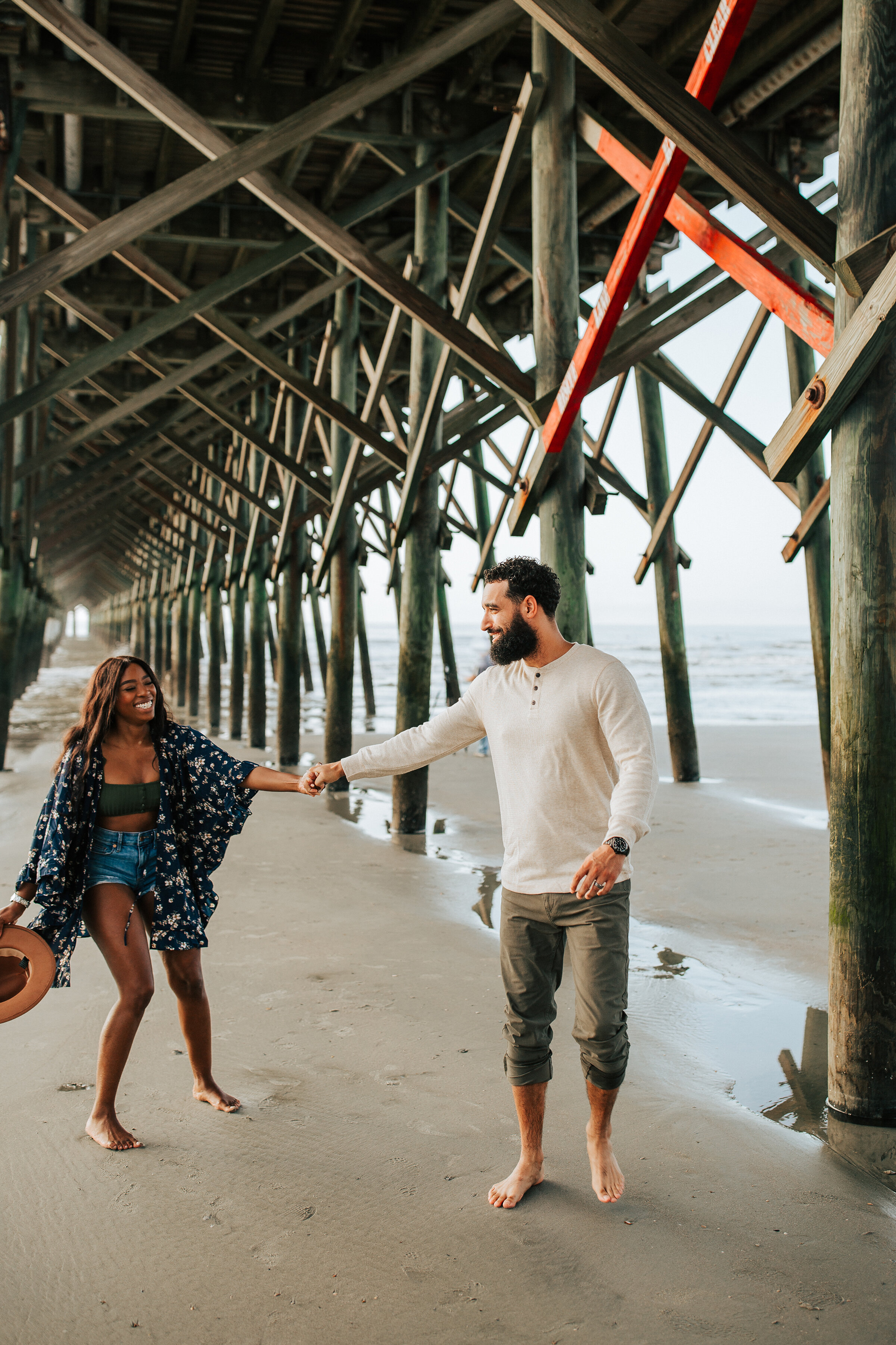  Beautiful couple play under the dock in a unique and fun engagement session by Emily Jenkins Photography. Summer engagement session inspiration ideas and goals location inspiration casual client attire inspiration ideas and goals summer goals couple