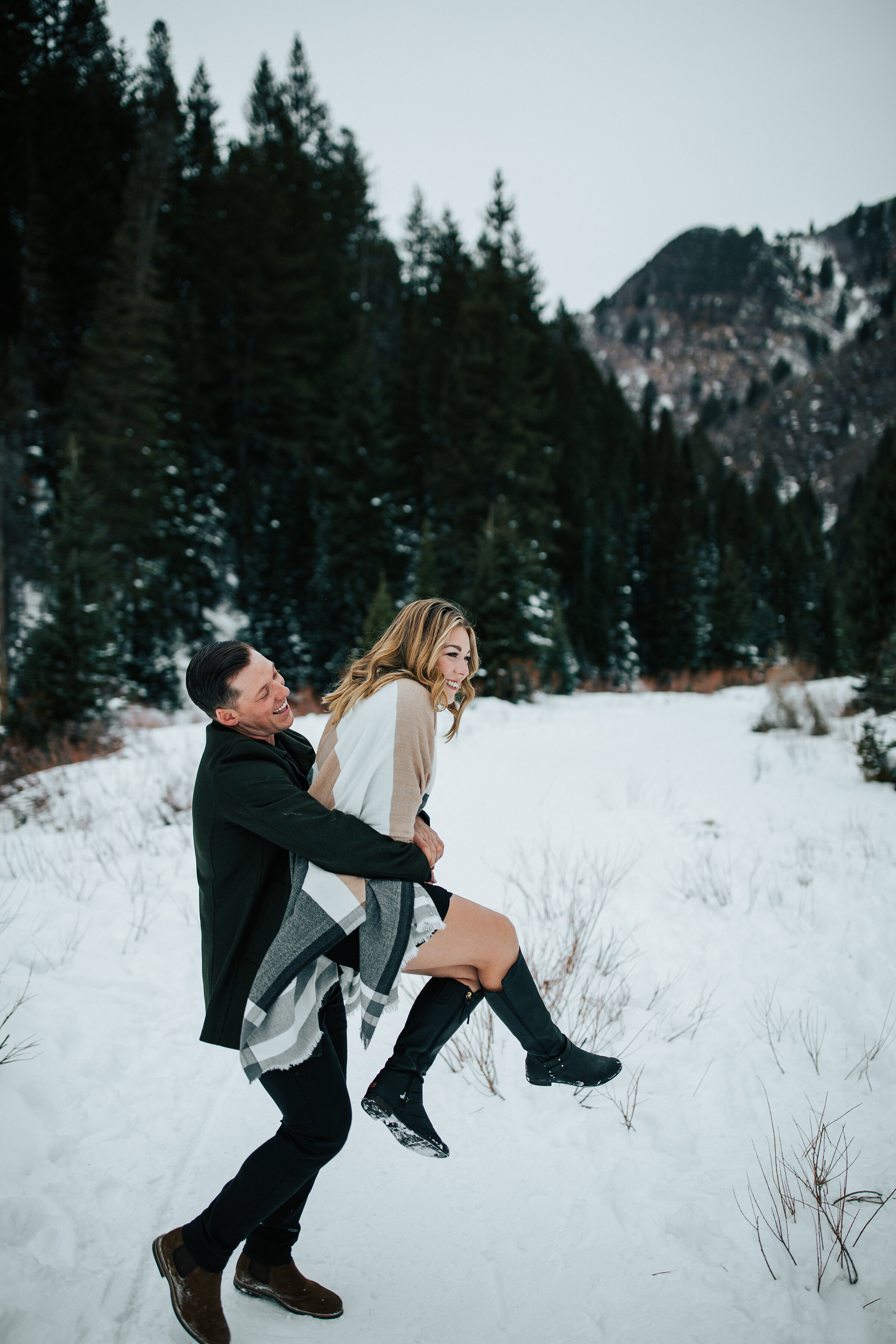  A playful couple romp in the snow in a winter engagement session by Emily Jenkins Photography.  Playful couple pose inspiration winter engagement session attire inspiration ideas and goals winter engagement couple goals women’s winter attire goals w