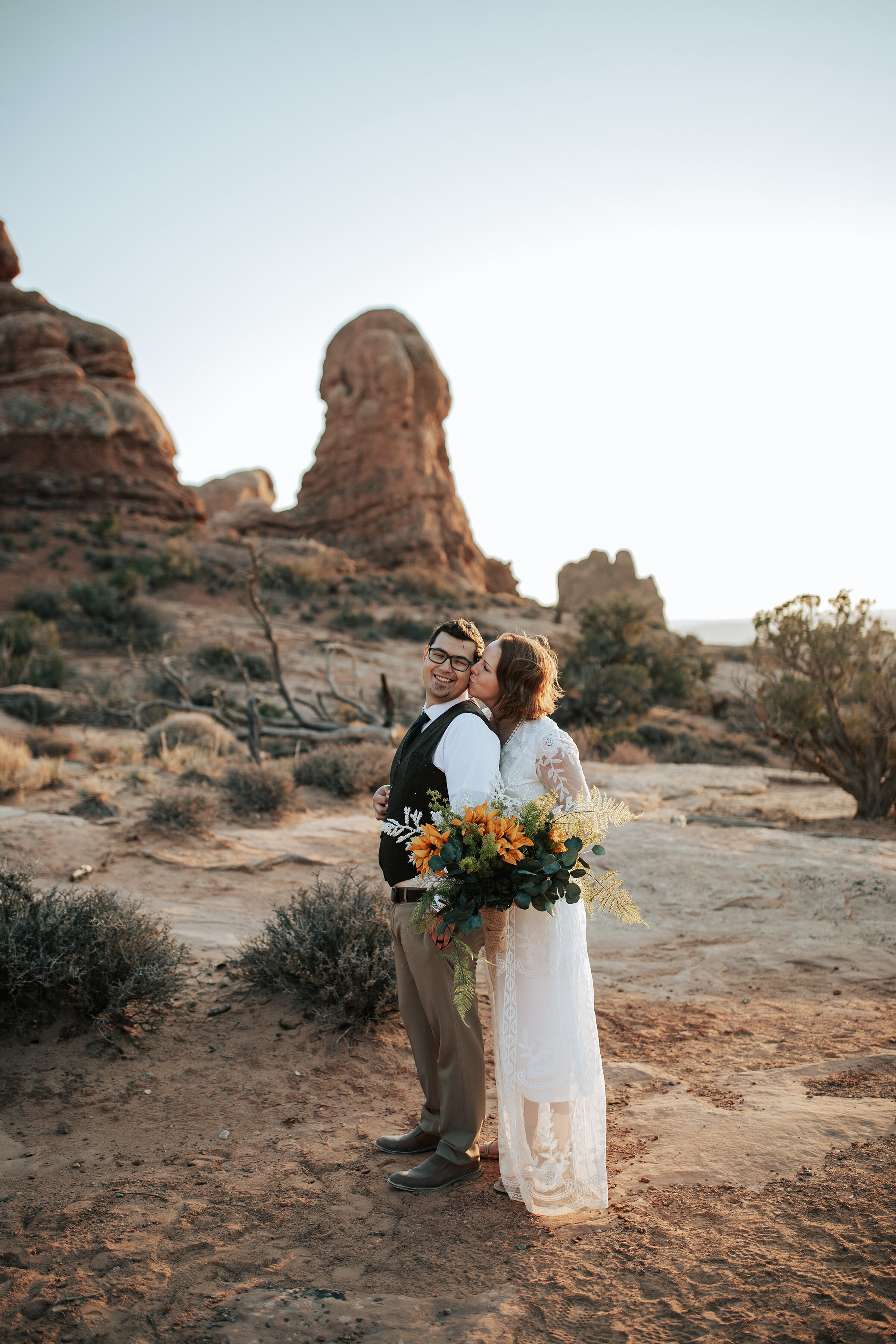  A beautiful bride kisses her husband in the rocks of Utah in a stunning elopement styled photo shoot by Emily Jenkins Photography. Elopement styled photo shoot inspiration elopement attire inspiration for men and women outdoor photo shoot location i