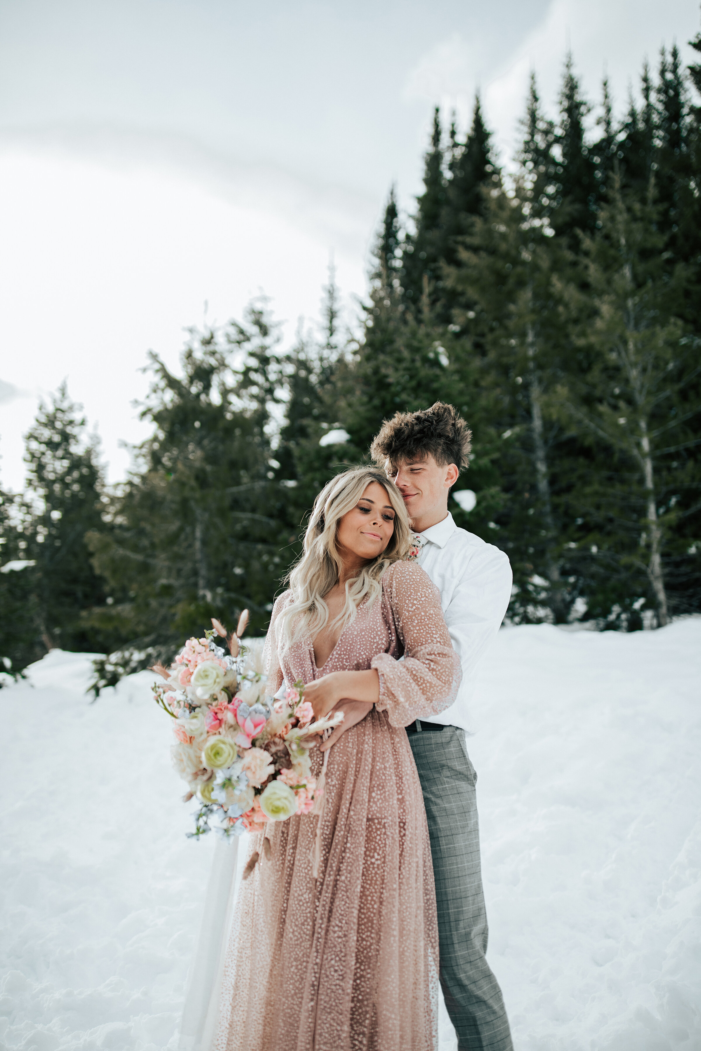  A beautiful couple hold each other as they stand in the snow in a beautiful winter themed elopement photo shoot in Utah. Non traditional wedding dress inspiration perfect for elopements wedding attire inspiration ideas and goals for modern brides br
