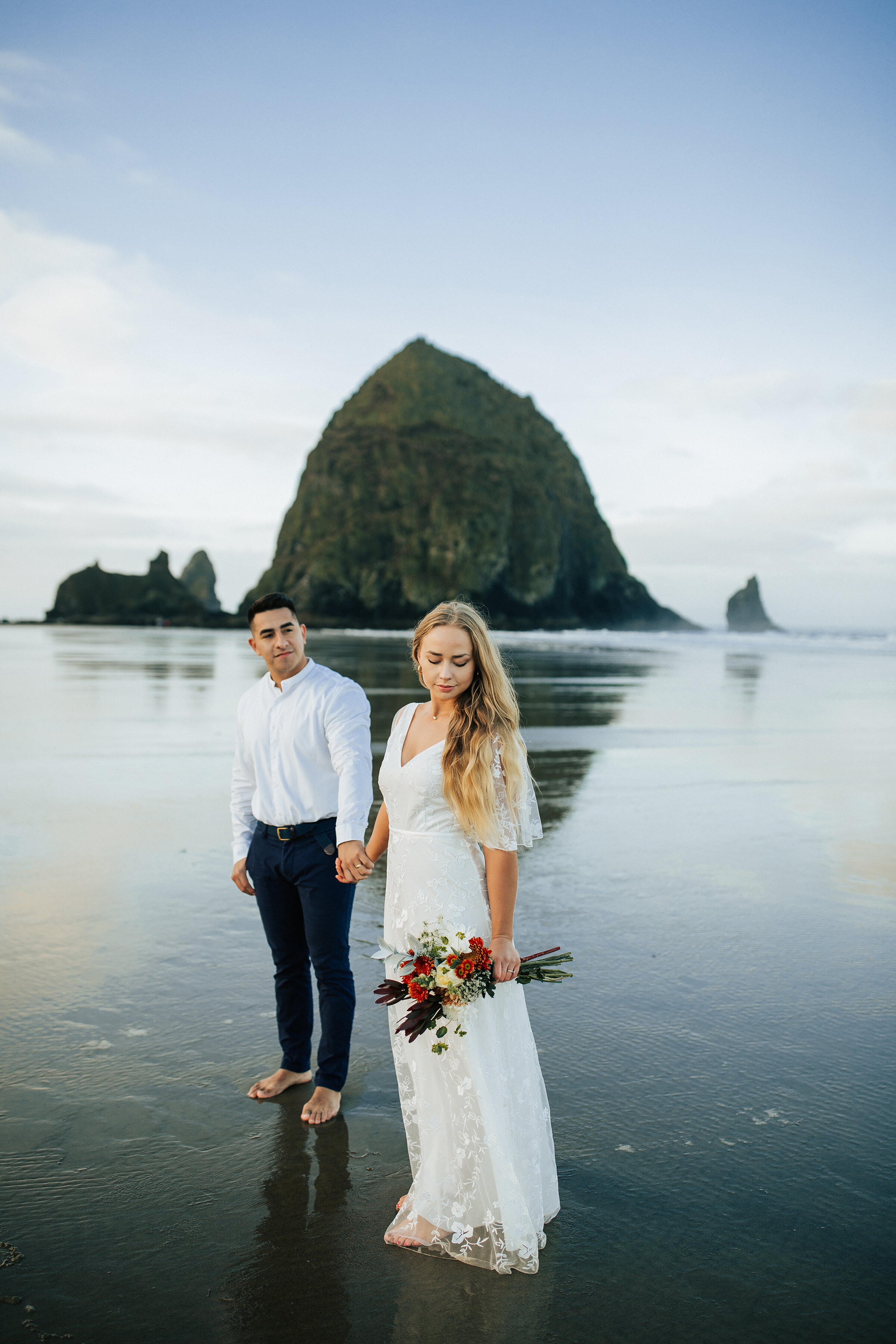  A handsome groom looks at his beautiful wife on the Oregon Coast in a romantic elopement styled photo shoot by professional photographer Emily Jenkins Photography. Elopement attire inspiration for men and women simple rustic bouquet inspiration idea