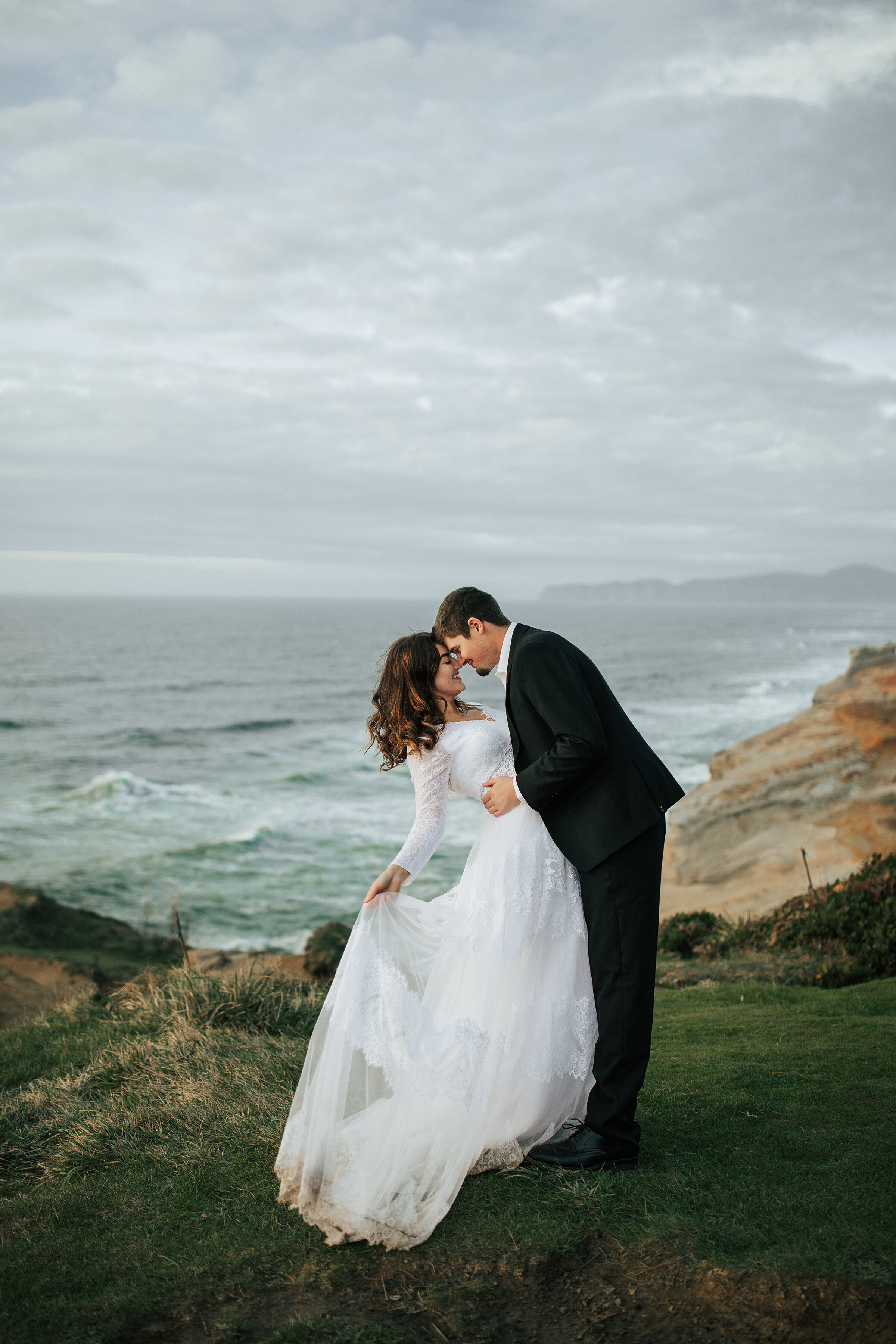  A newly eloped couple dance on the Oregon Coast in a stunning and romantic elopement photo shoot by Emily Jenkins Photography. Romantic wedding dress inspiration elopement attire inspiration ideas and goals couple goals couple pose inspiration ideas