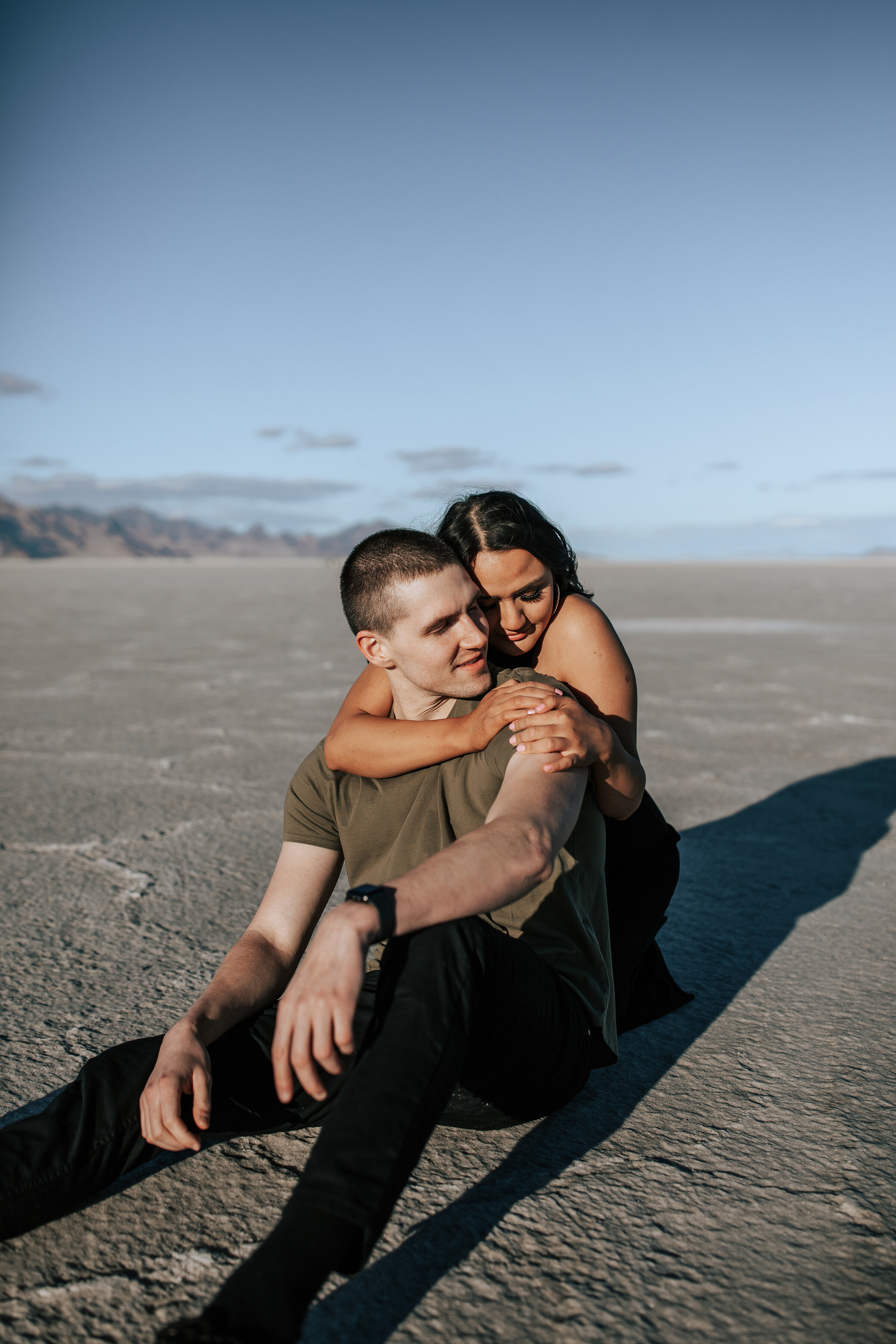  A beautiful couple sit together in the sand  in a beautiful engagement session  in Utah by Emily Jenkins Photography. Professional Utah photographer couple goals couple pose inspiration Utah photo shoot location inspiration ideas and goals outdoor c