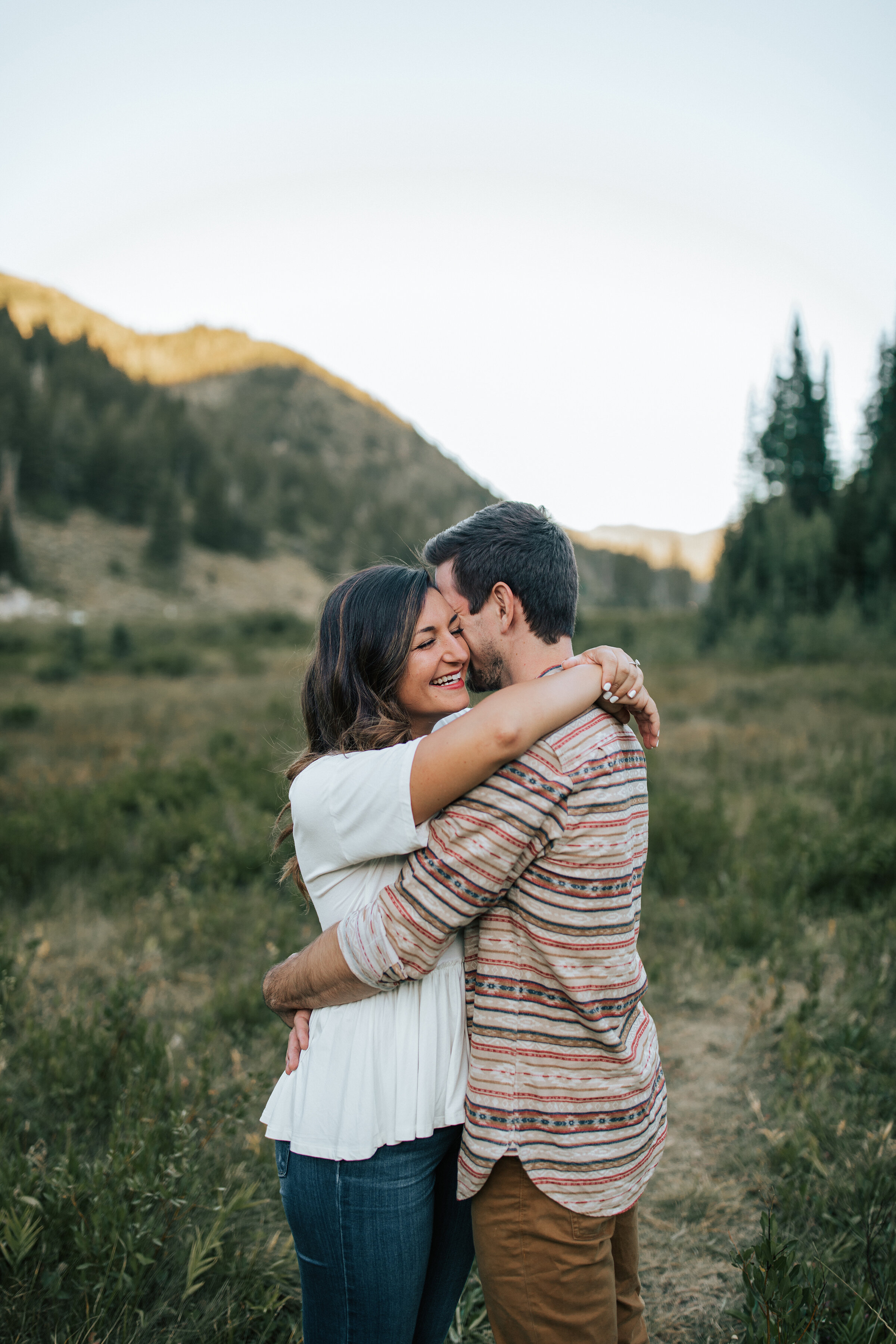 Engaged couple hug in the grassy field in a beautiful engagement session by professional photographer. Emily Jenkins Photography close couple pose inspiration standing couple pose casual client attire inspiration ideas and goals outdoor engagement p