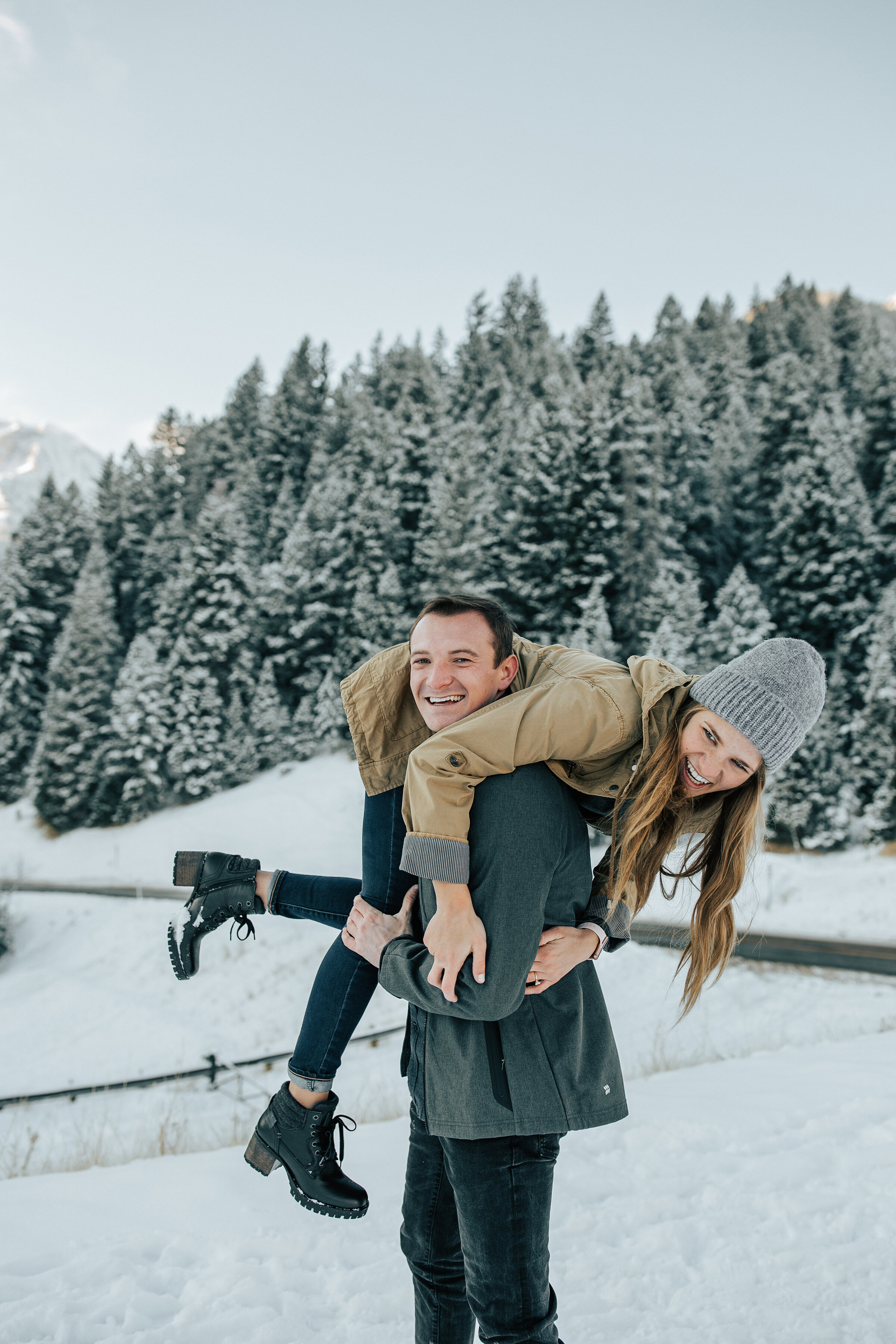  Playful couple wrestle in the snow in a snow covered engagement session by professional Utah photographer Emily Jenkins Photography. Winter engagement session inspiration ideas and goals snow covered trees winter engagement attire inspiration ideas 