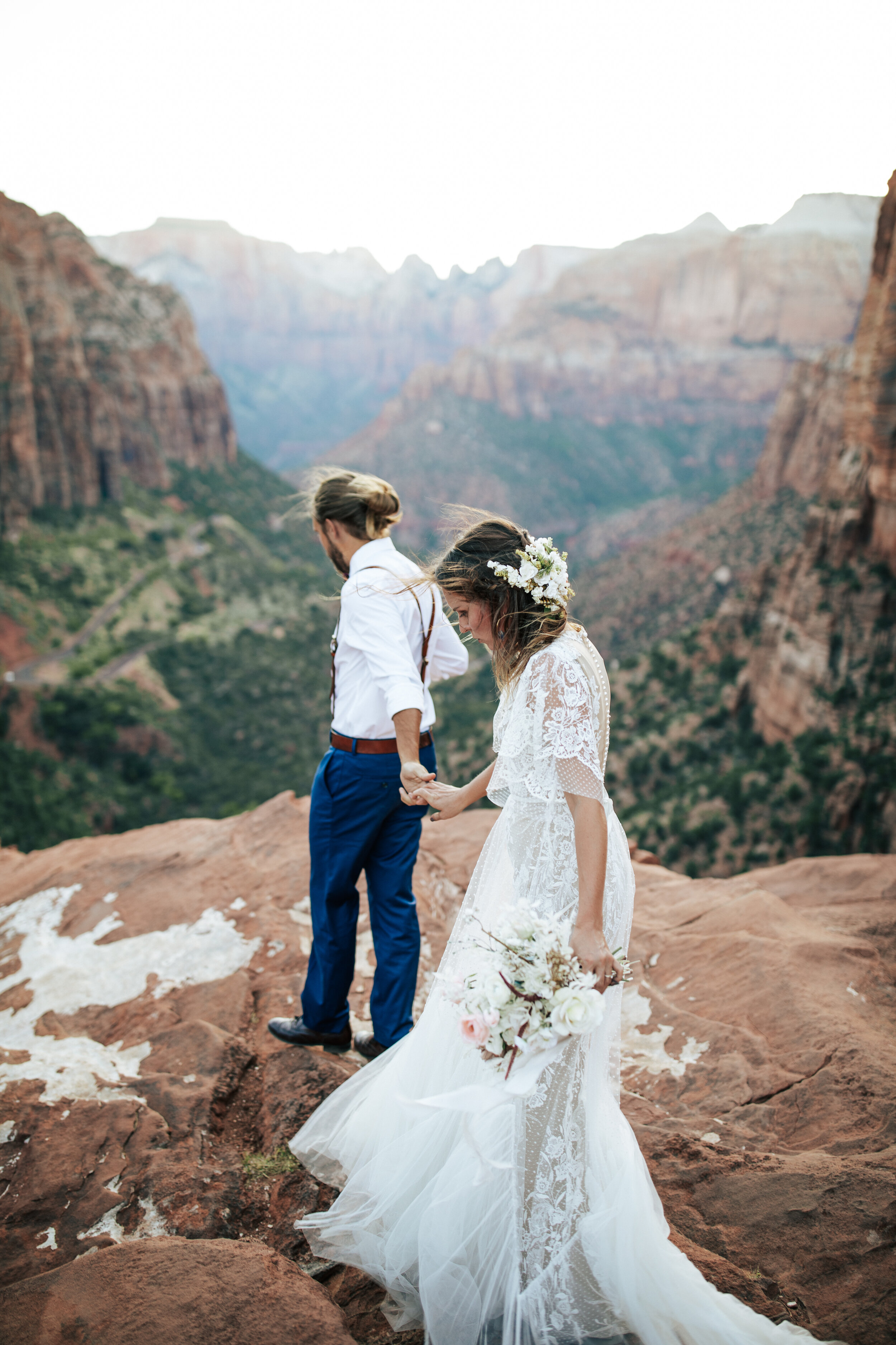  A groom leads his stunning bride to the edge of the rock face in a beautiful outdoor elopement photo shoot in Zion National Park, Utah by Emily Jenkins Photography. Wedding aesthetic inspiration ideas and goals for outdoor weddings elopement goals c