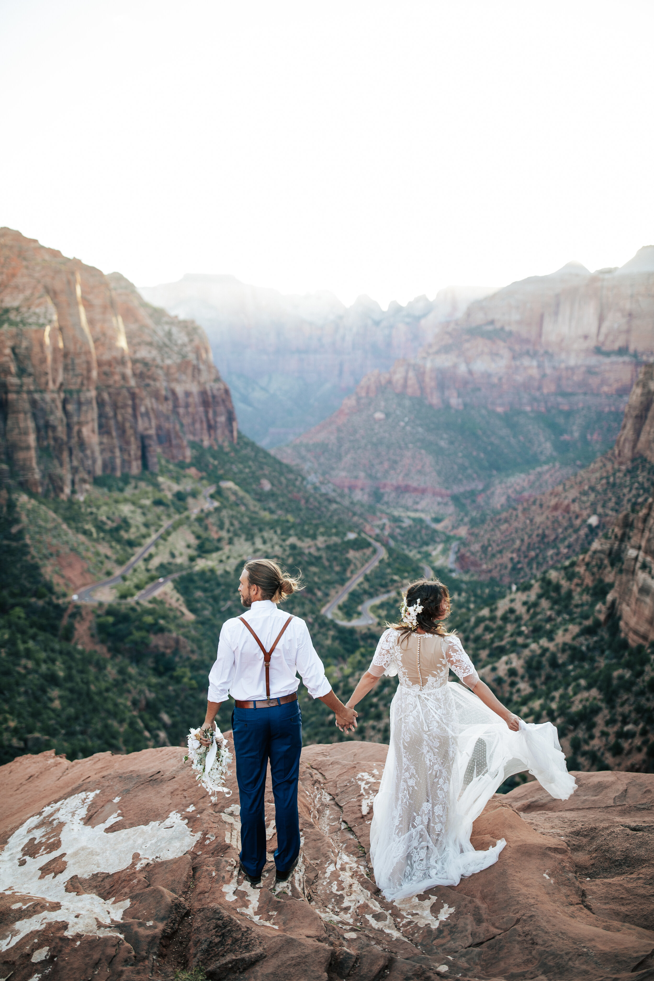  A newly married couple look out a the beautiful scenery as they hold hands in a stunning elopement styled photo shoot by Emily Jenkins Photography in Zion National Park. Utah elopement location inspiration ideas and goals outdoor wedding inspiration