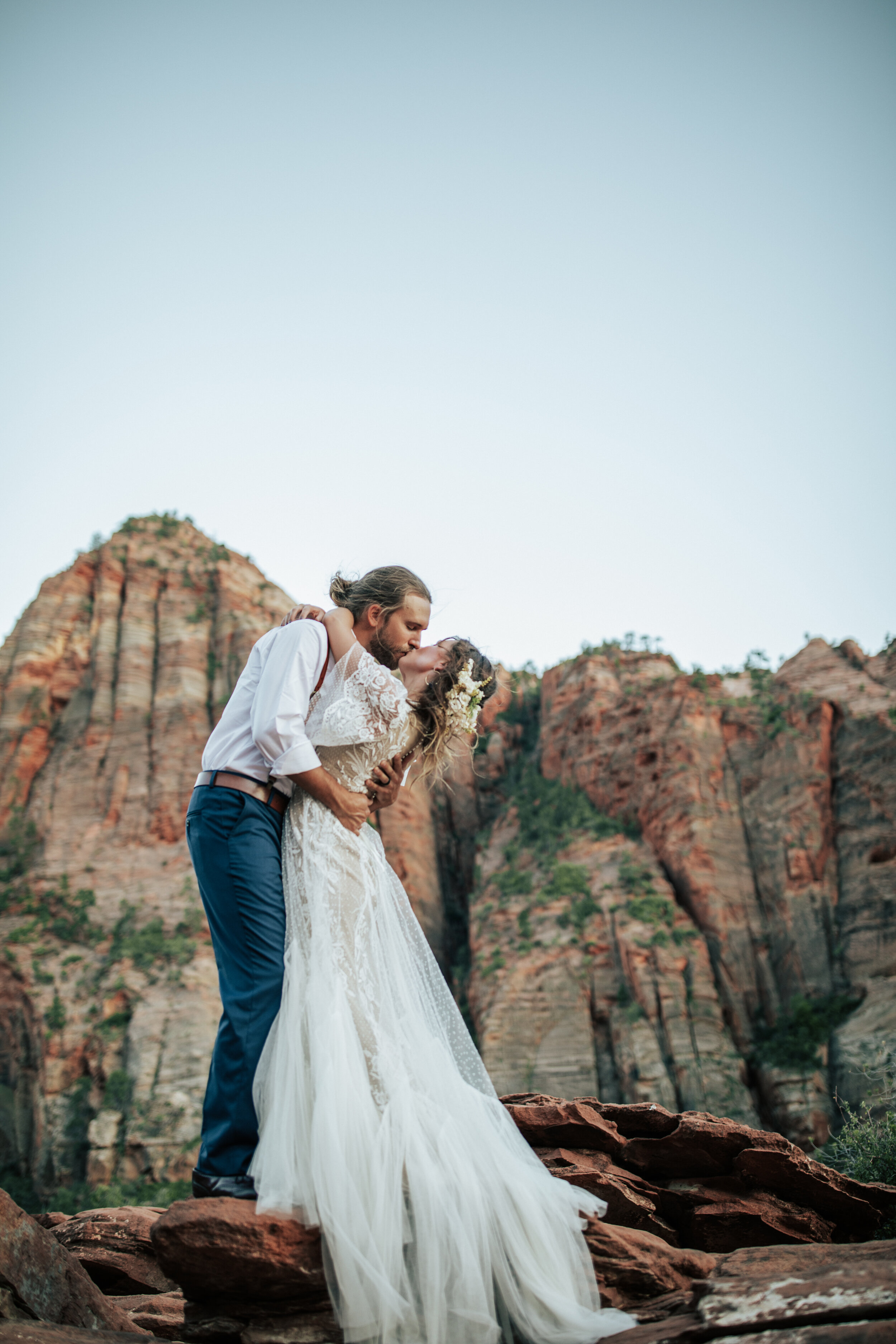  A handsome groom dips his bride as the kiss on the cliffs of Zion National Park, Utah in elopement styled photo shoot by professional wedding photographer Emily Jenkins Photography. Wedding picture inspiration ideas and goals outdoor photo shoot ins