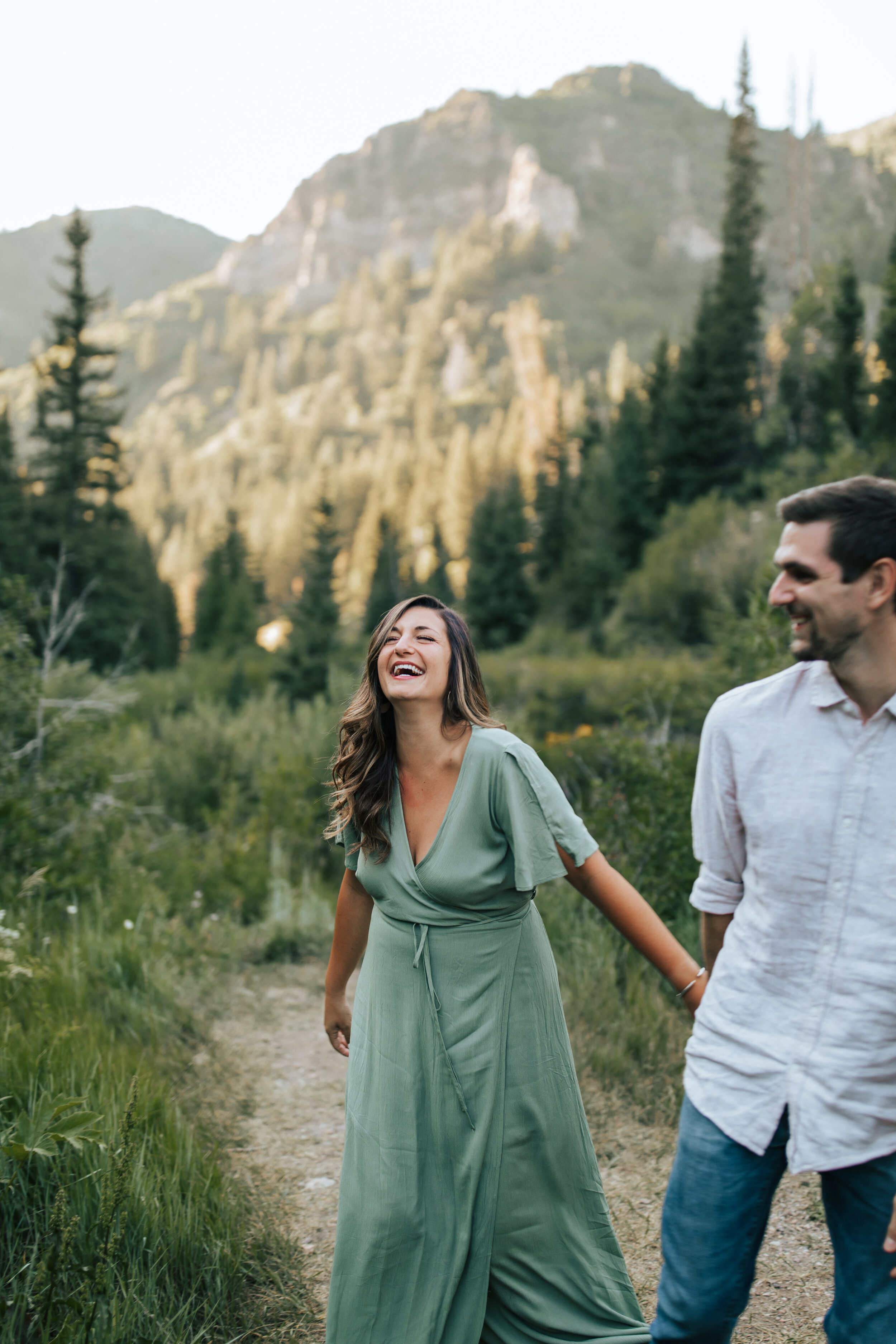  Park City Photographer Emily Jenkins takes a photo of a couple holding hands and laughing in the green Utah mountains. Utah mountain photography utah photography spots earthy tone photography emiy jenkins photography couple style inspiration green d