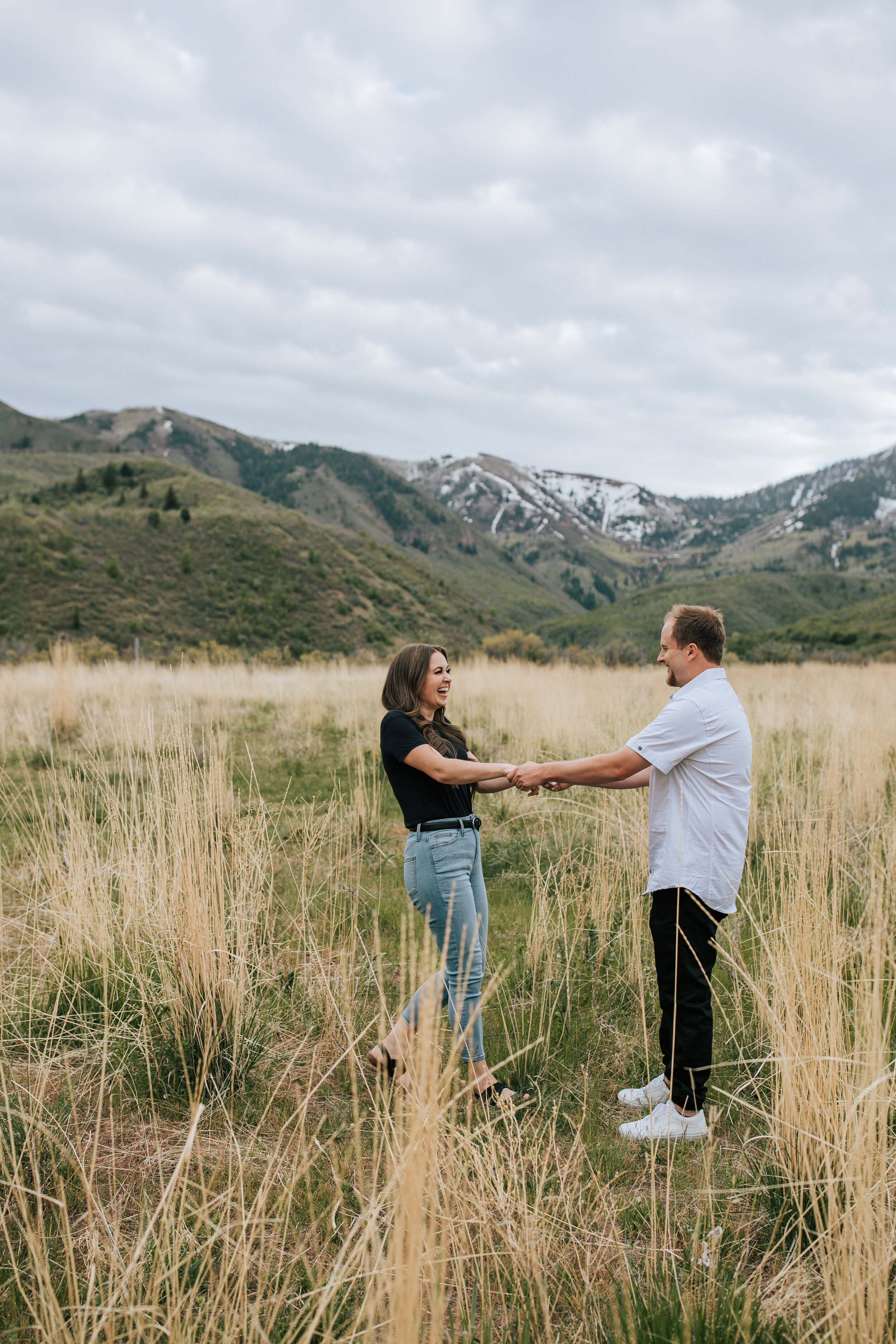  Couple holding hands in a field of yellow grass and blue beautiful Utah Mountains in the backdrop taken by Emily Jenkins Photography. Mountain couple shoot park city mountain photo utah couple photographer emily jenkins photos utah mountains yellow 