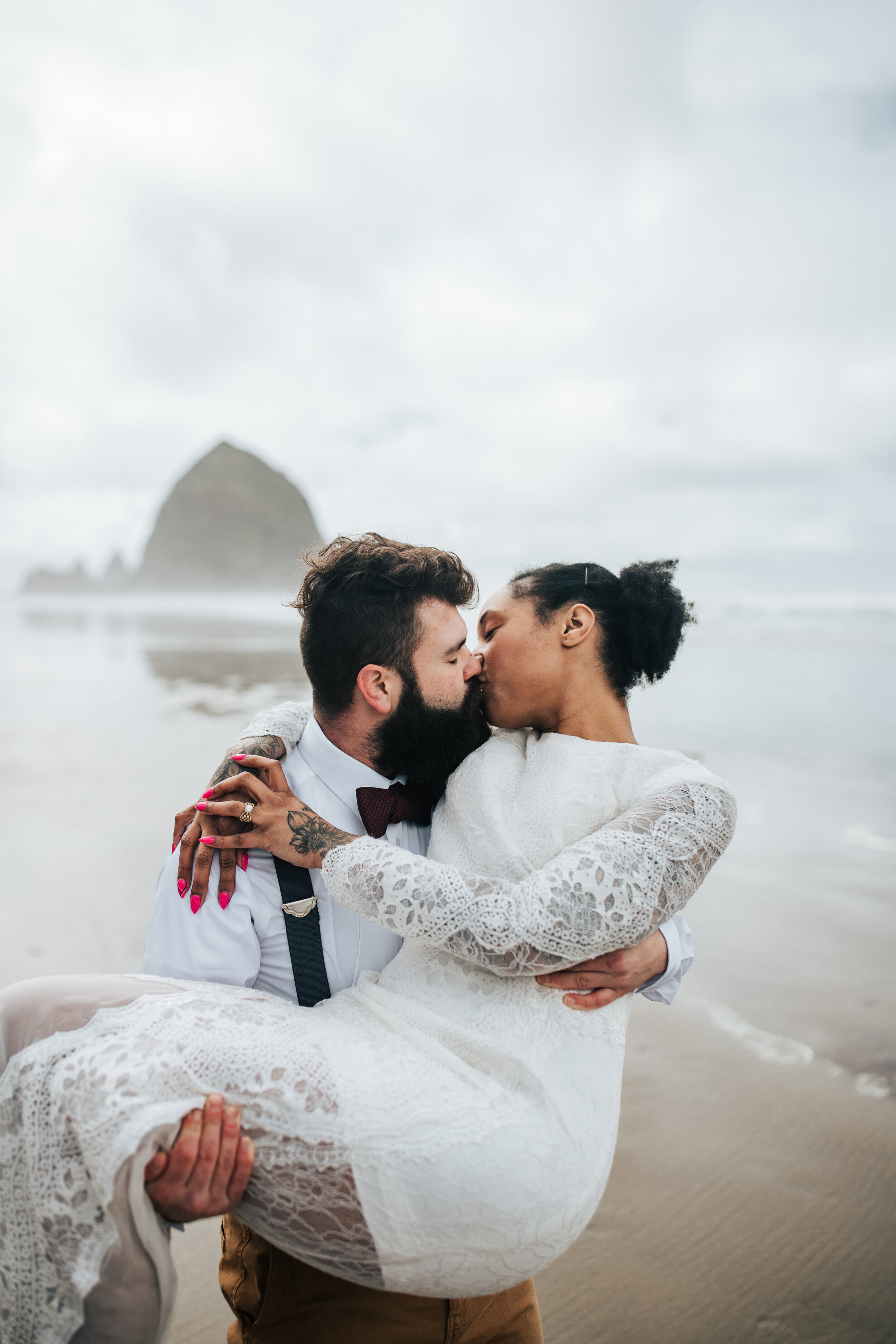 Eloping on the Oregon coast with keyhole back wedding dress. Man and woman hold hands at Cannon Beach, Oregon walk along the beach Oregon coast elopement photographer for adventurous couple #EmilyJenkinsPhotography #cannonbeach #elopementphotographe