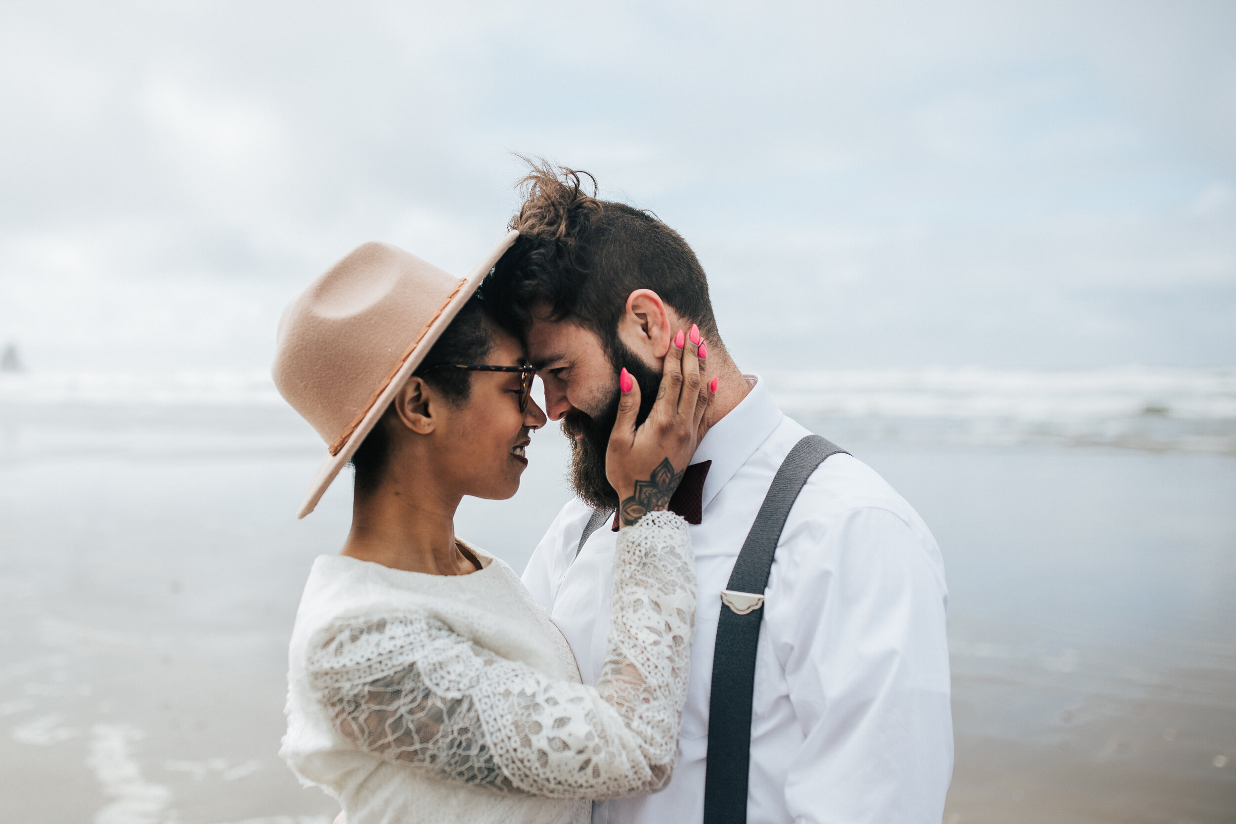  Eloping on the Oregon coast with keyhole back wedding dress. Man and woman hold hands at Cannon Beach, Oregon walk along the beach Oregon coast elopement photographer for adventurous couple romantic beach elopement #EmilyJenkinsPhotography #cannonbe