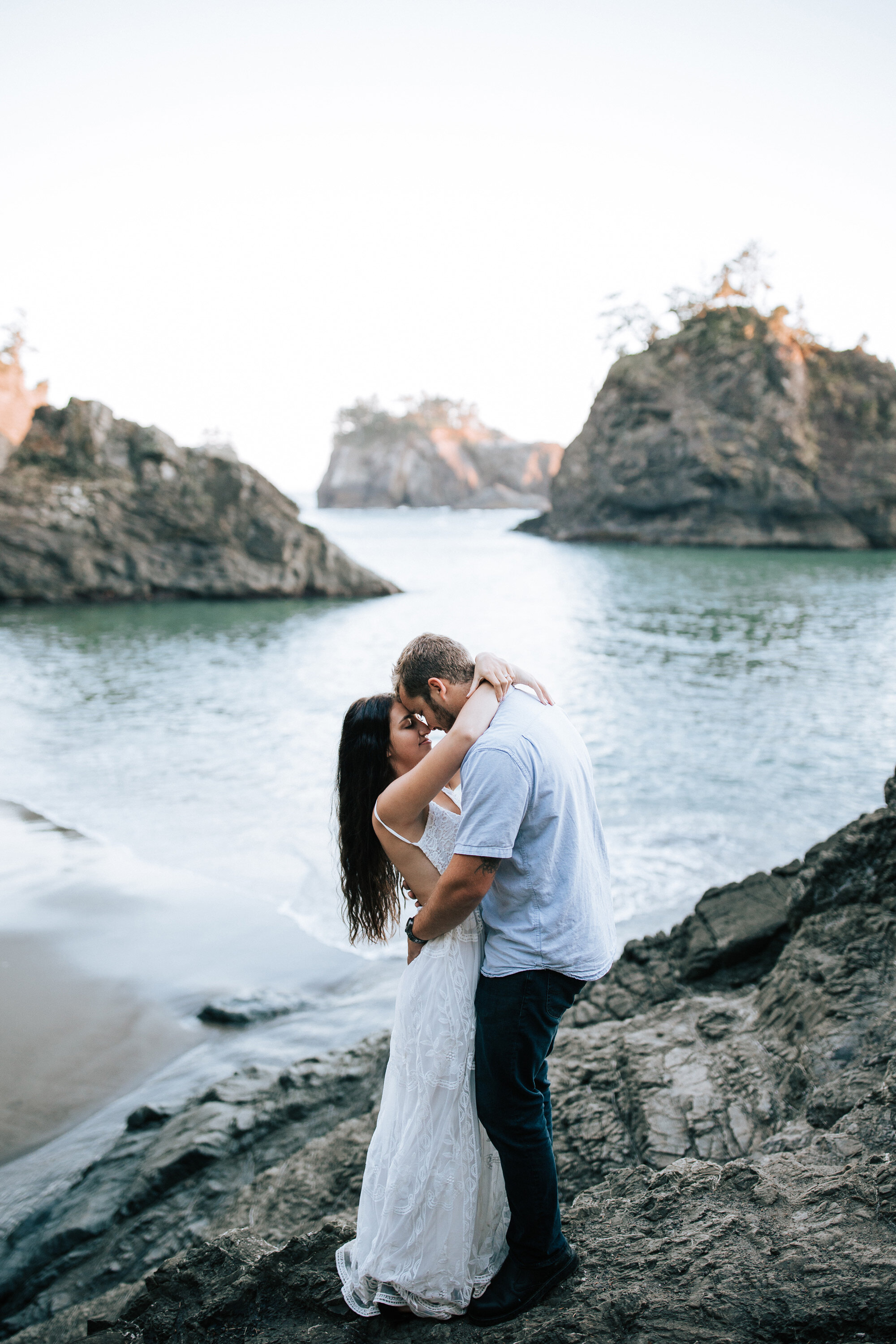  Breath-taking photo of a couple during an elopement on Brookings Beach with their heads together and arms wrapped around one another by Emily Jenkins Photography. elopement beach photos hidden private beach photos Oregon coast towns #emilyjenkinspho