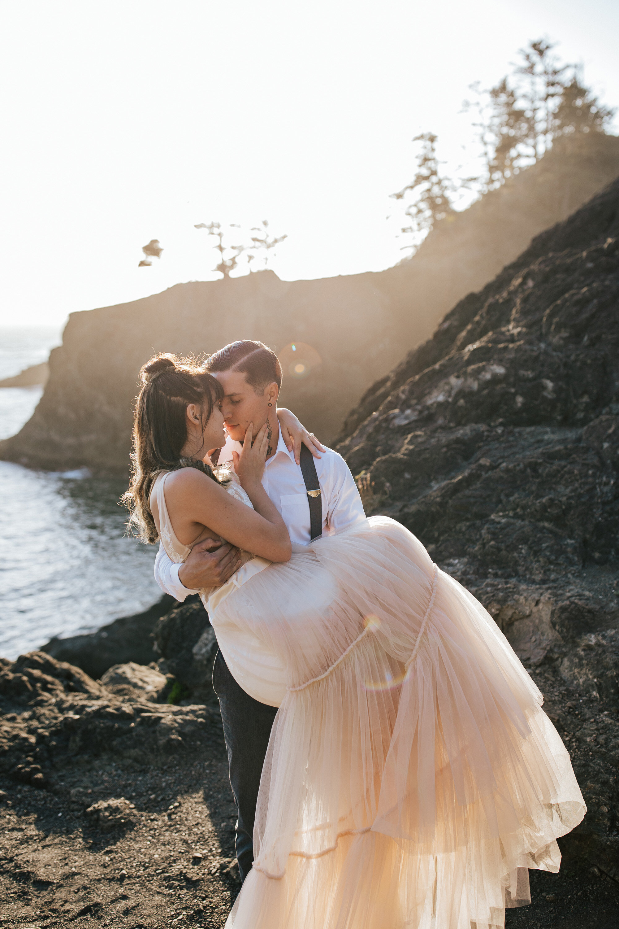  On the coast of Brookings, Oregon Emily Jenkins Photography captures a man holding his bride in his arms as they snuggle in close during a small town elopement. uncrowded beaches for elopements sunrise elopement photography #emilyjenkinsphotography 