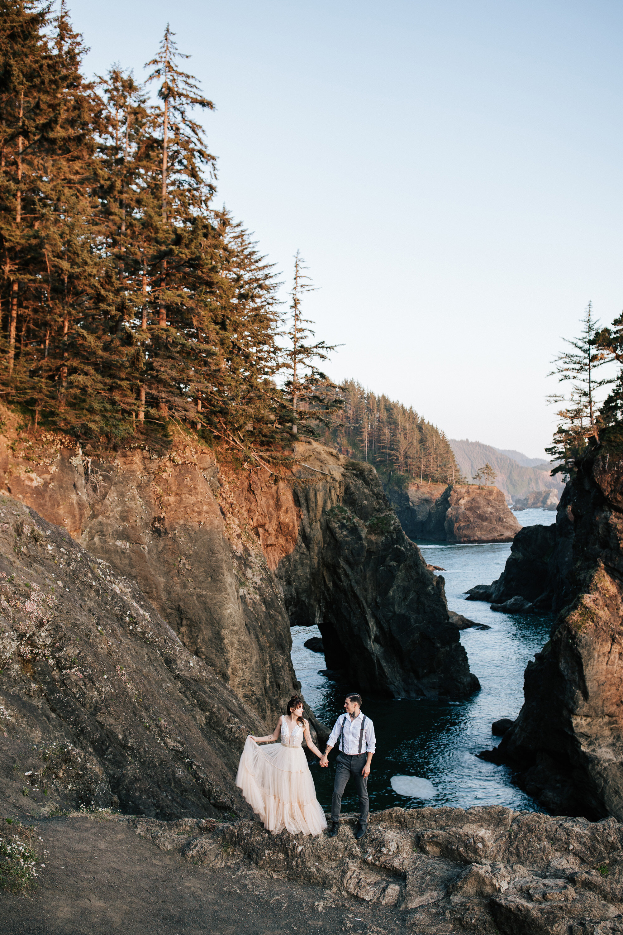  Portrait of a couple on the Oregon Coast holding hands and walking on a rock cliff by Emily Jenkins Photography during an elopement in Brookings, Oregon. couple elopement portraits ocean cliff beaches private secluded beaches for weddings #emilyjenk