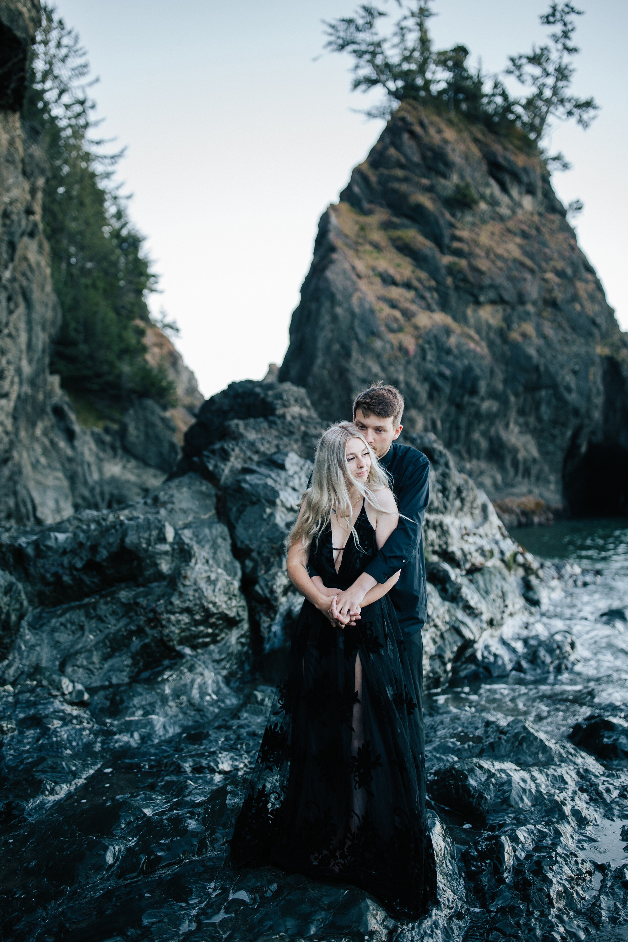  Emily Jenkins Photography captures a couple during an elopement with a woman wearing a black deep v spaghetti strap dress and groom in black button-down shirt on the Brookings, Oregon beach. brookings beach rocky beach photography black dress and sh