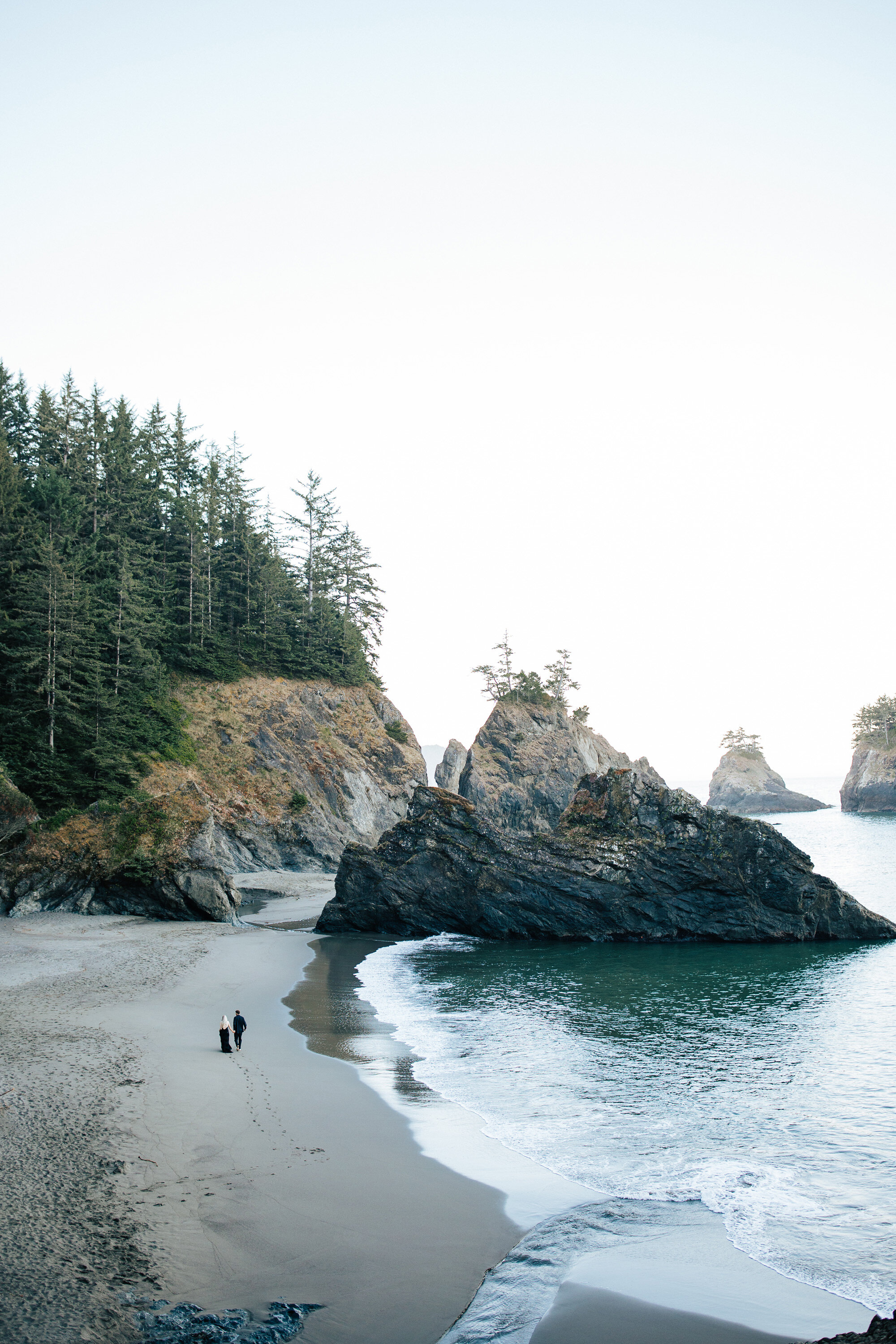  Scenic shot of a couple walking along a beach in Brookings, Oregon with long shallow beach perfect for a private elopement by Emily Jenkins Photography. best elopement beaches blue-green beach for wedding #emilyjenkinsphotography #emilyjenkinselopem