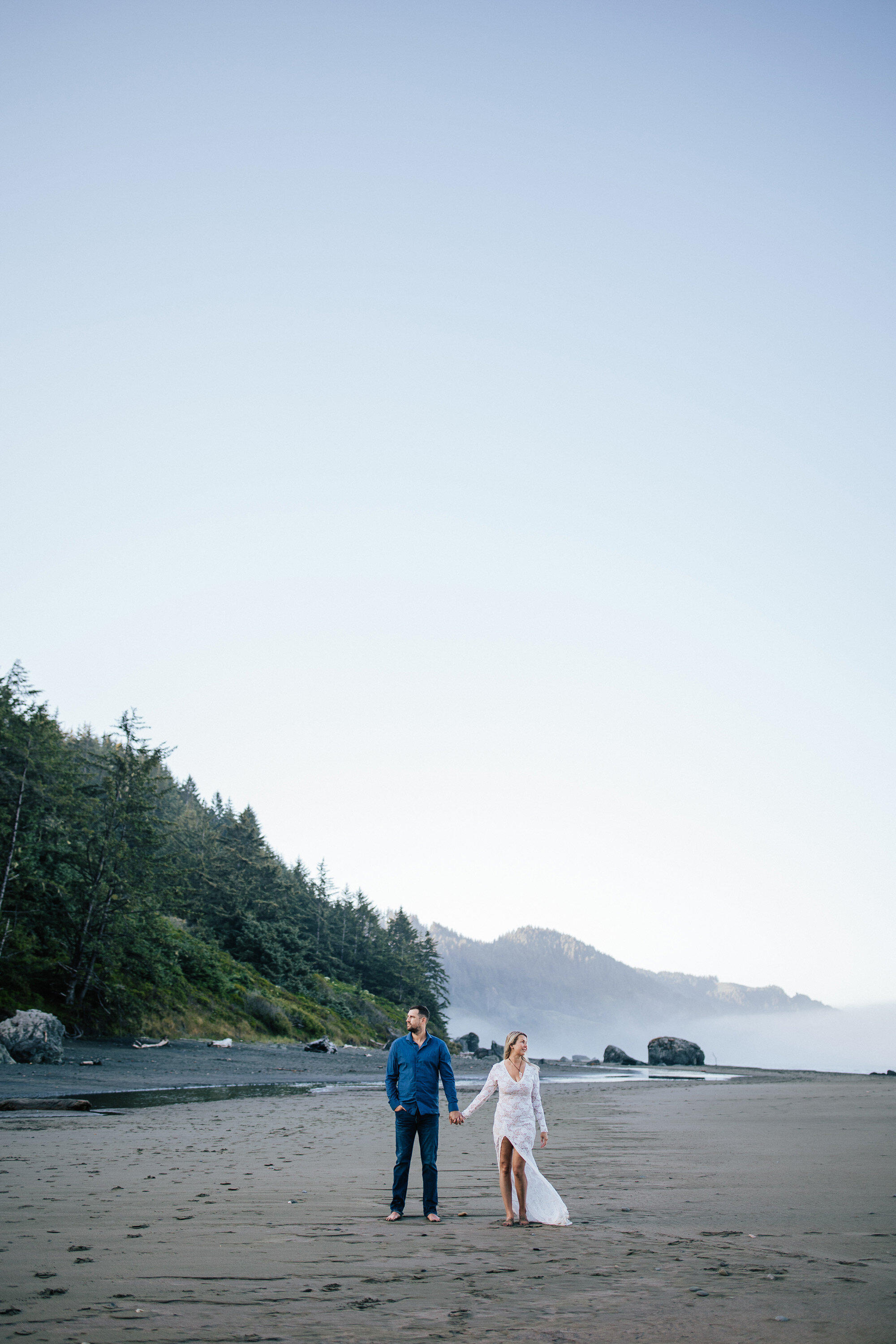  Perfect moderate weather elopement location Brookings, Oregon beach featuring clear blue skies and big sandy beach with a couple holding hands by Emily Jenkins Photography. big sandy beach elopement moderate weather year-round elopement locations #e