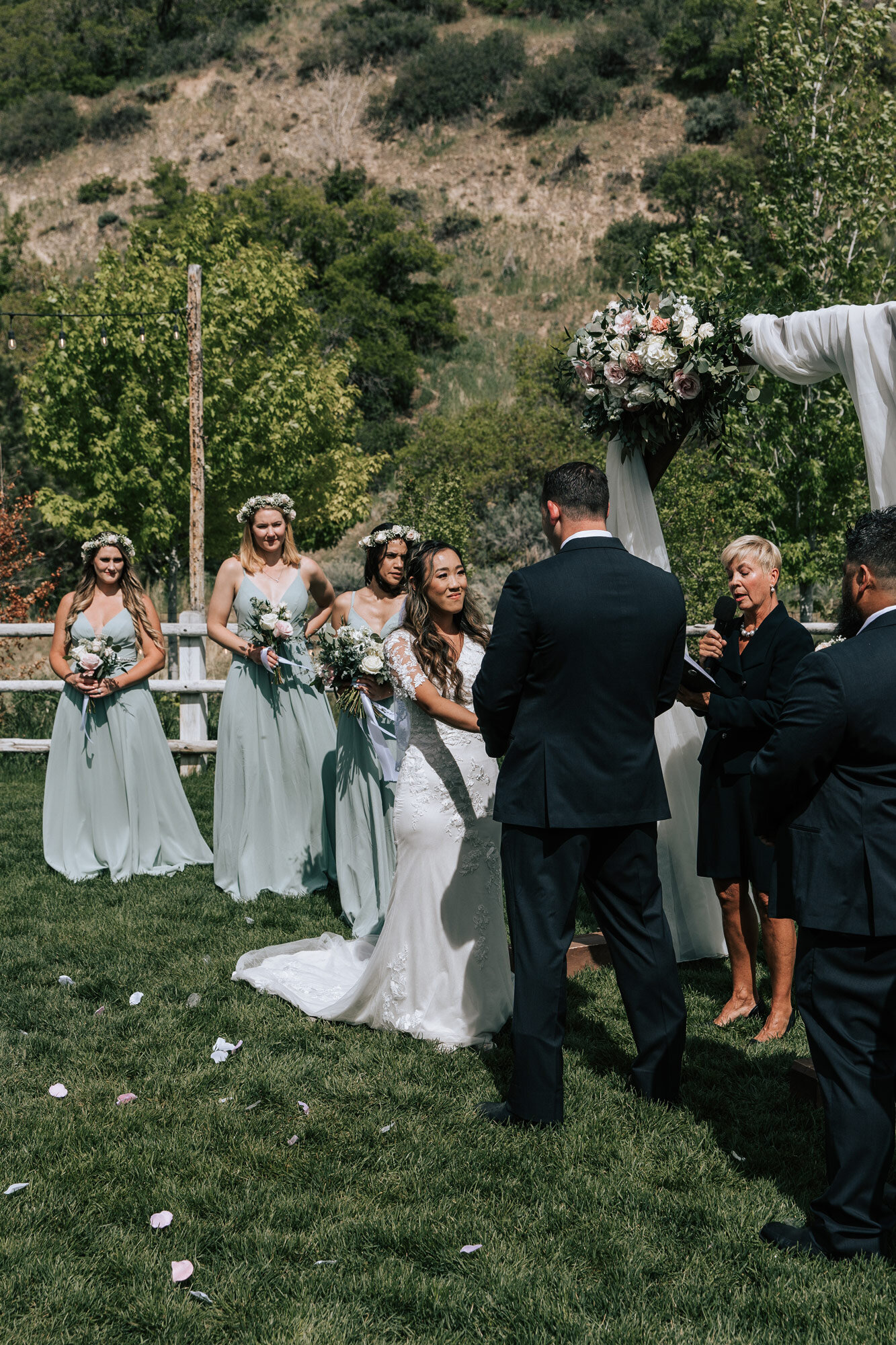  At Quiet Meadow Farms Emily Jenkins Photography captures a bride holding her groom’s hands as they say wedding vows during an outdoor ceremony. bridesmaid dress style muted green dress vows #emilyjenkinsphotography #emilyjenkinsweddings #utahwedding