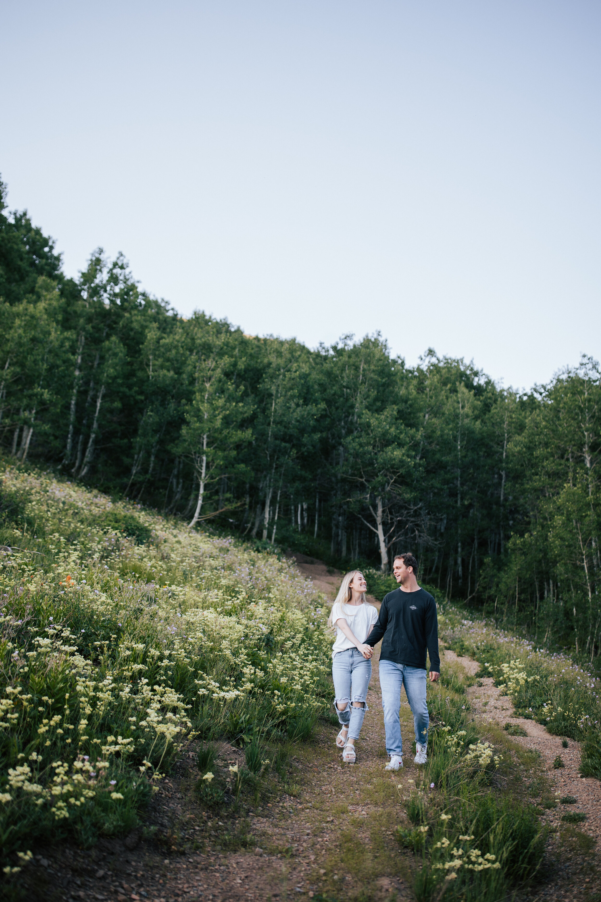  Engagement session in wildflowers in the mountains near Park City, Utah. Summertime engagement photos with mountain views. Engaged couple walk together in the mountains. Outfit inspo. Engagement outfits. #engagementphotos #engagements #weddingphotog
