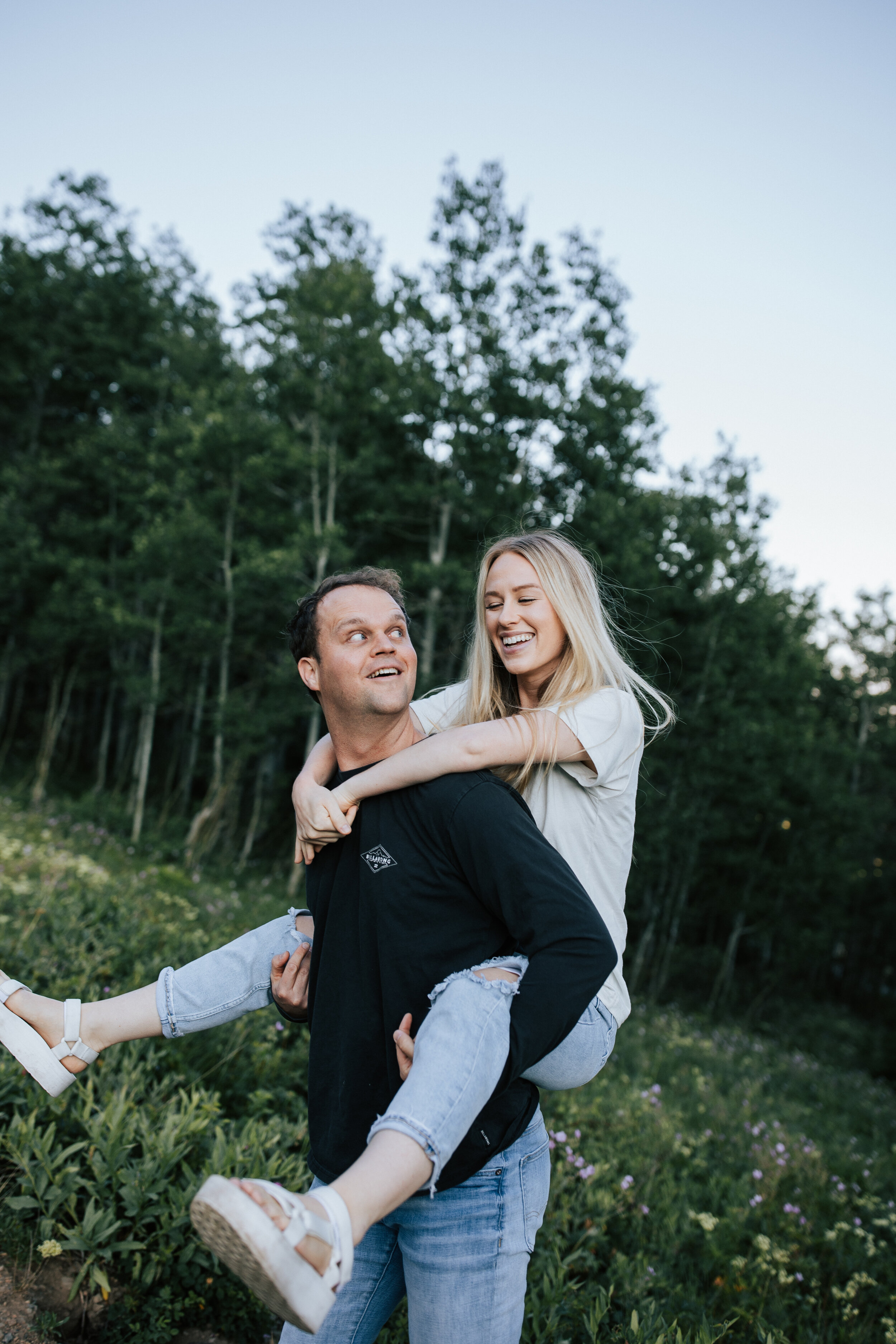  Engagement session in wildflowers in the mountains near Park City, Utah. Summertime engagement photos with mountain views. Engaged couple doing a piggyback ride in the mountains. Outfit inspo. Engagement outfits. #engagementphotos #engagements #wedd