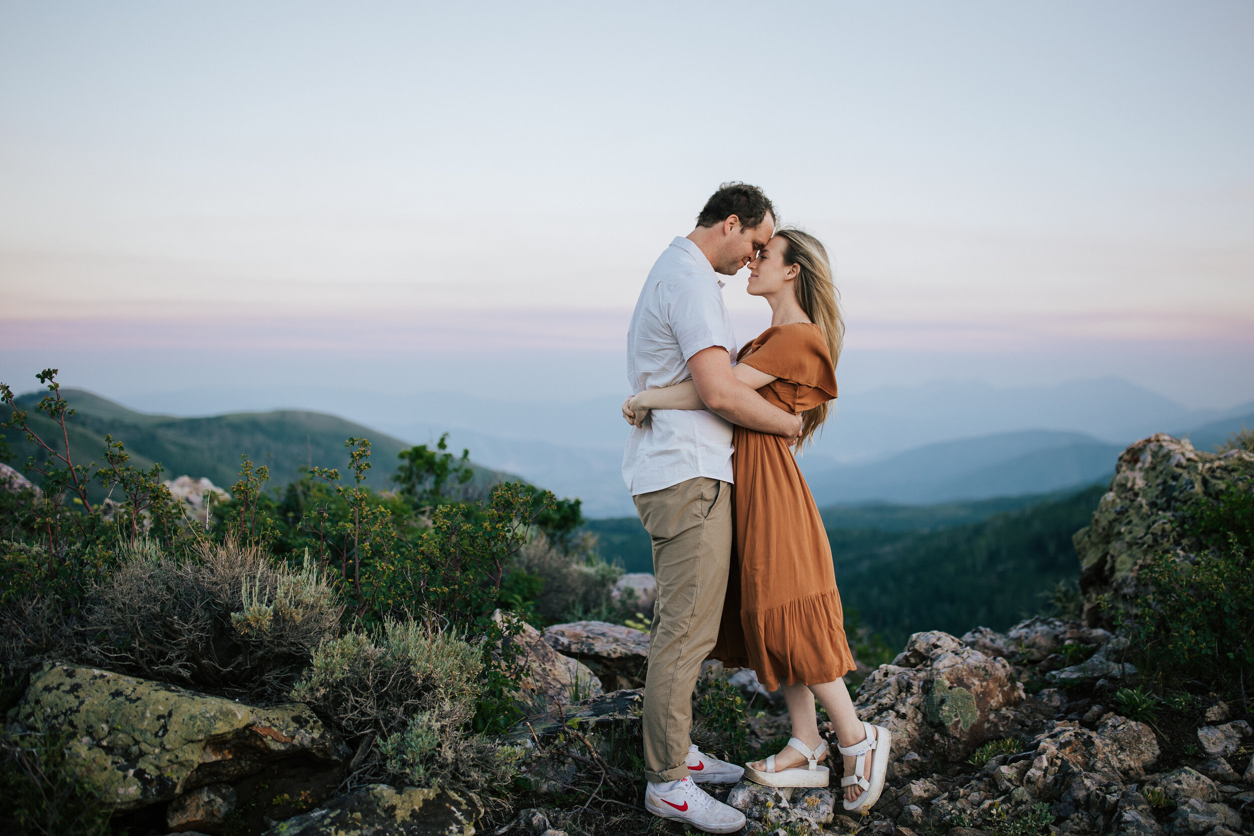  Engagement session in wildflowers in the mountains near Park City, Utah. Summertime engagement photos with mountain views. Engaged couple hug in the mountains. Outfit inspo. Romantic engagement session. Engagement outfits. #engagementphotos #engagem